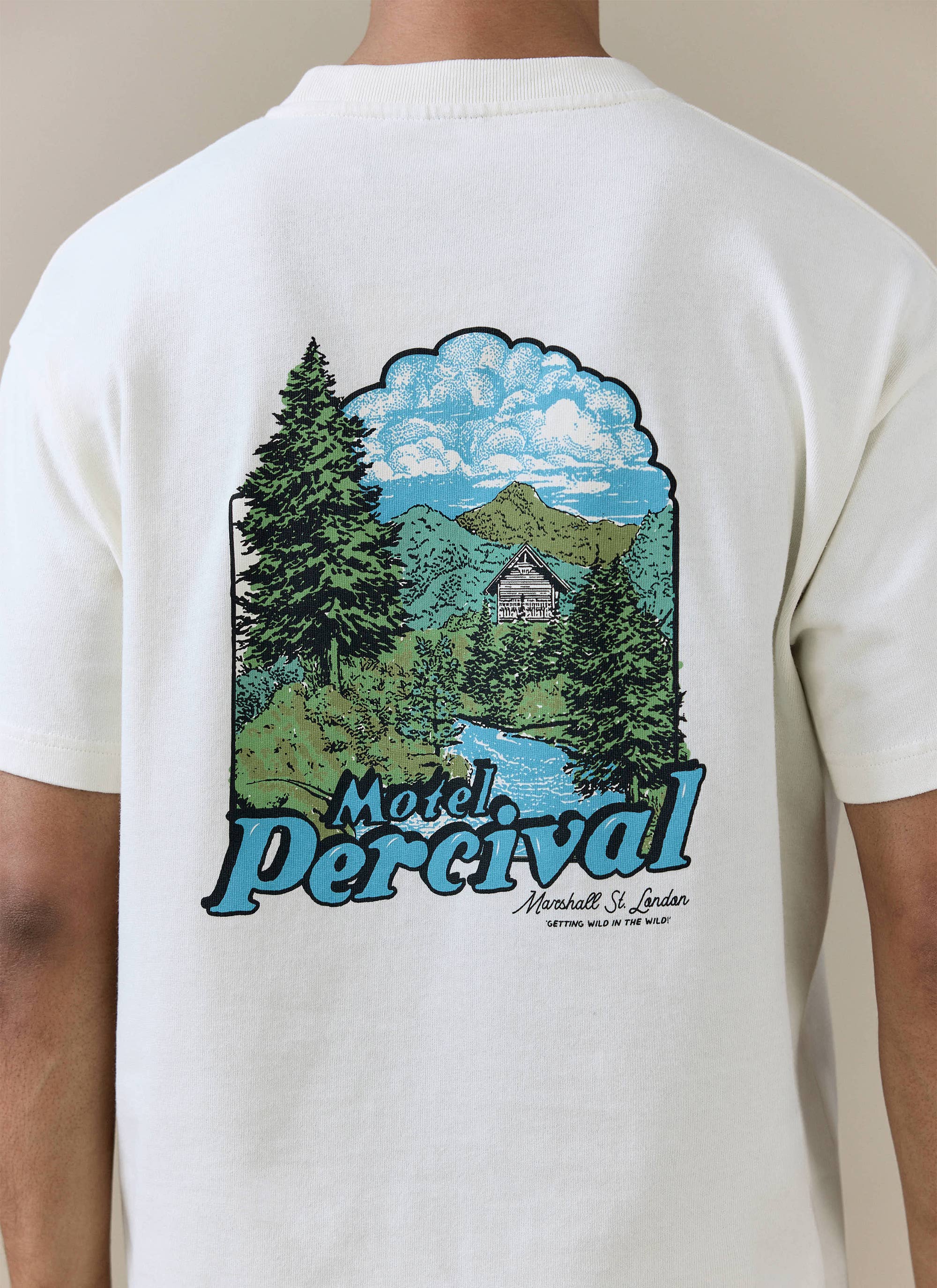 Back of the cream organic cotton Percival Arnold Oversized T Shirt with a mountain landscape and Motel logo graphic.