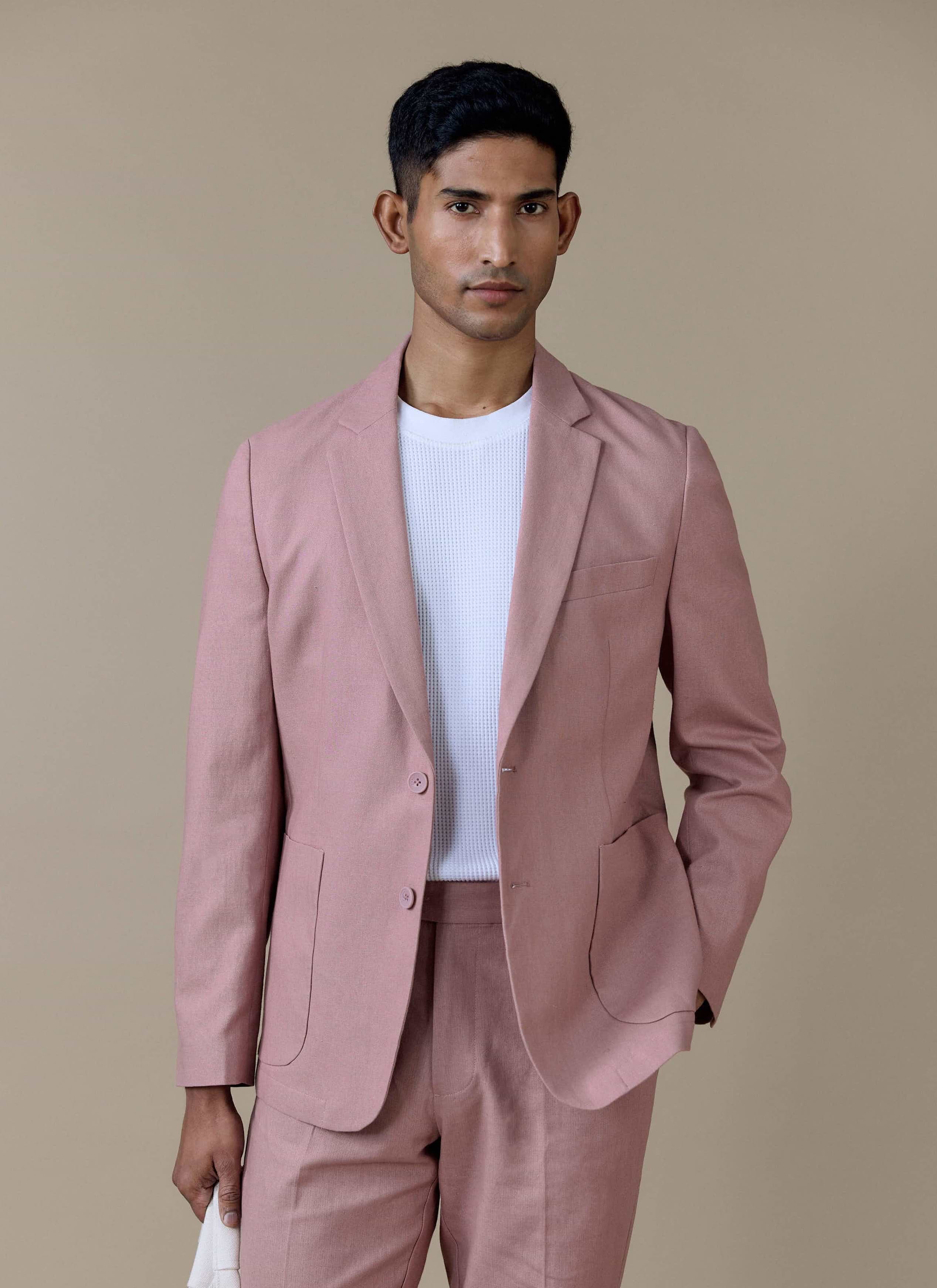 Tailored linen blazer in dusty pink by Percival, styled over a white knit top with matching tailored trousers.