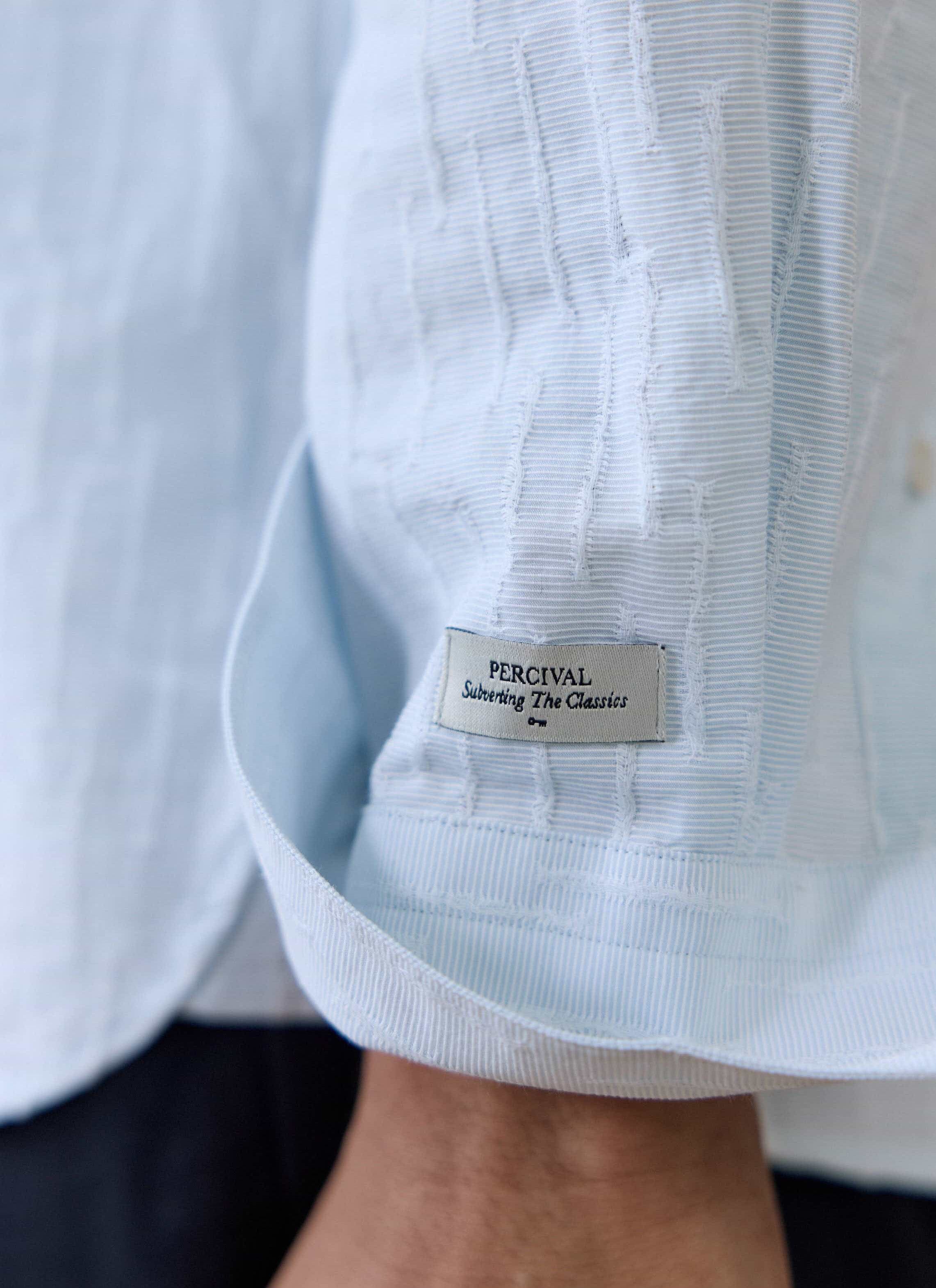 Close-up of the light blue Percival Paros Pearce Shirt, showing the textured seersucker fabric and brand label.