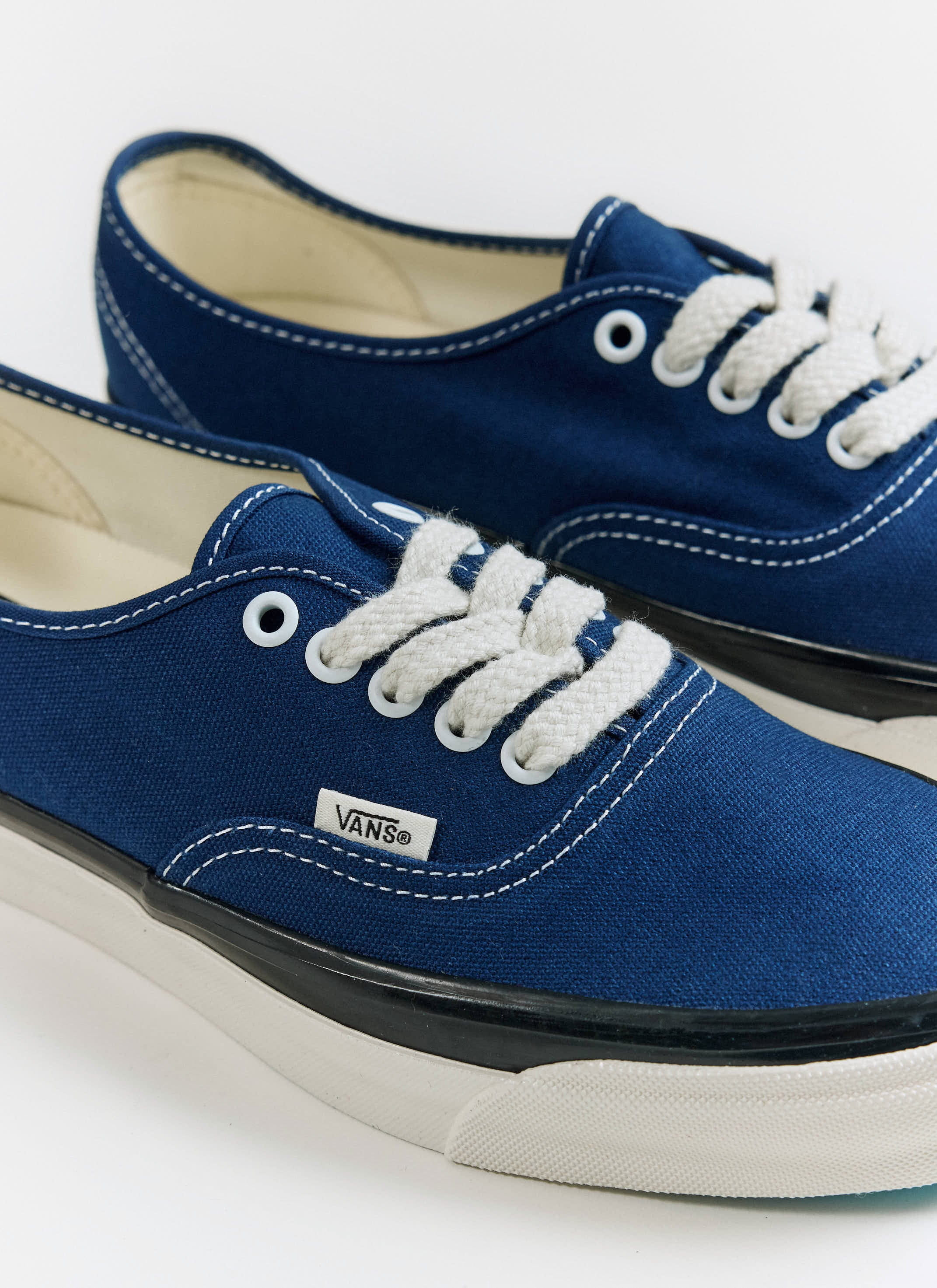 Close-up of the blue Vans Premium Authentic 44 shoes at Percival, showing the canvas upper and white laces.