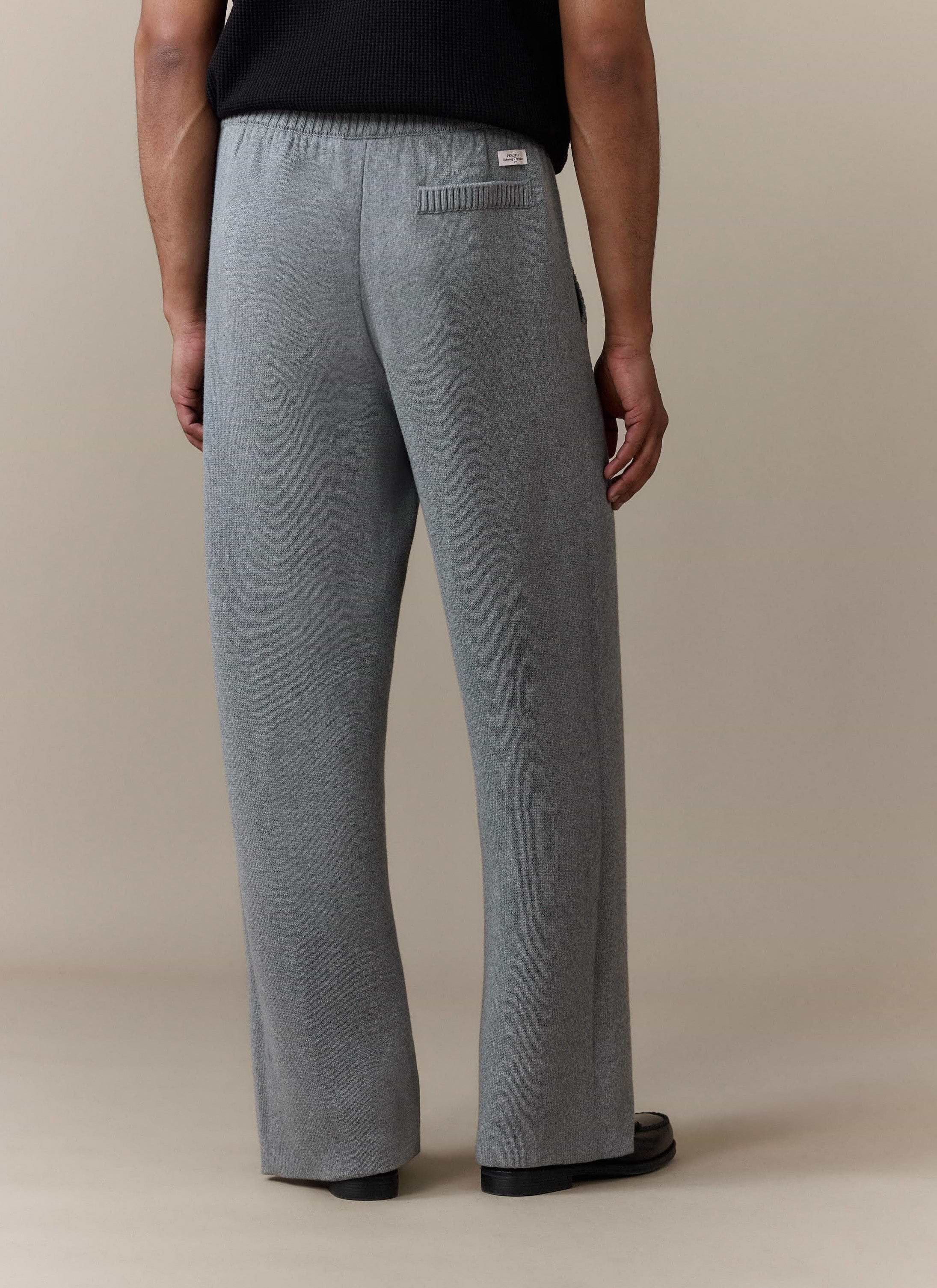 Back view of a model wearing the Percival Chronicle Knitted Straight Leg Trackpants in grey, showing the back pocket detail.