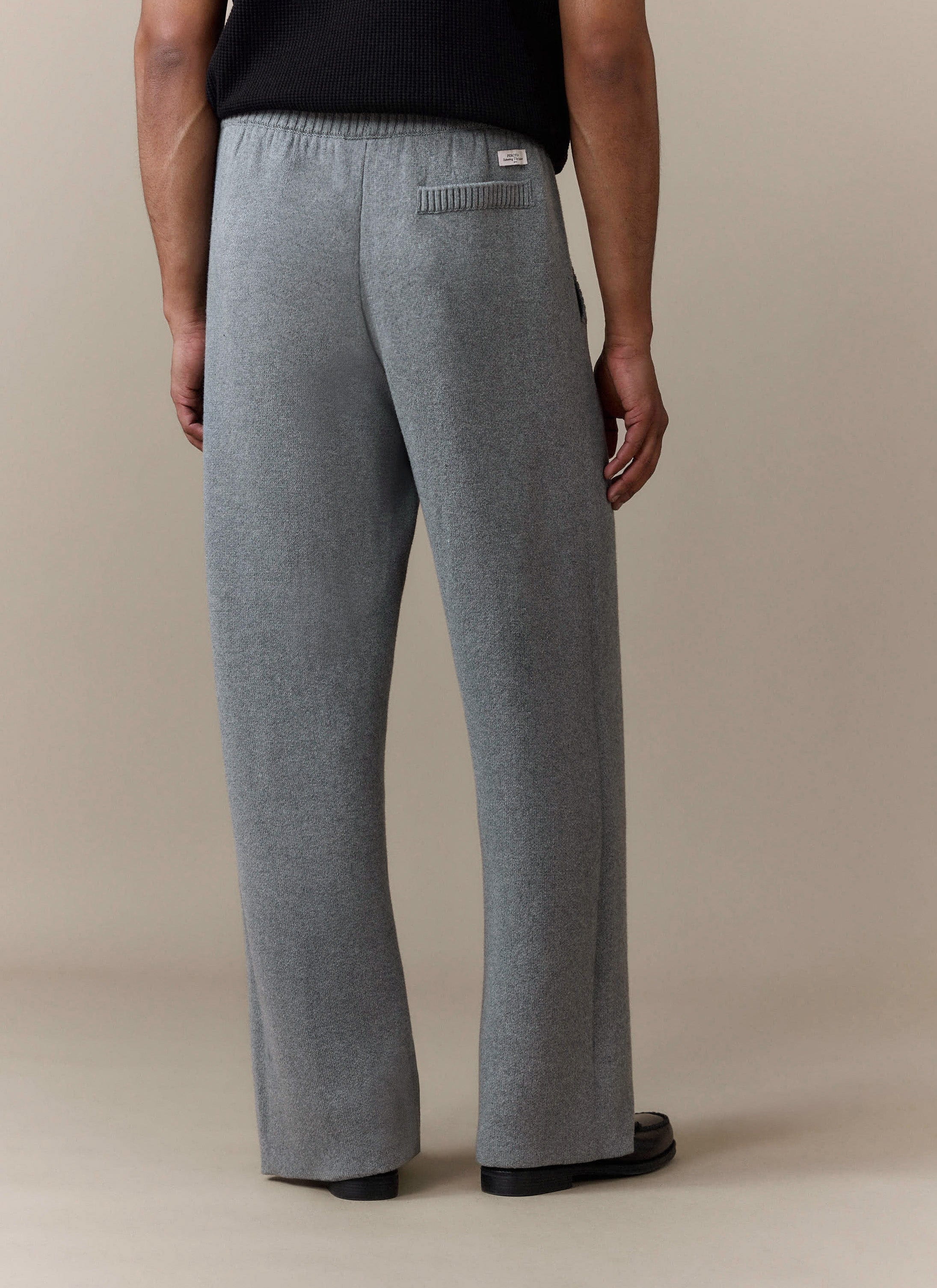 Back view of a model wearing the Percival Chronicle Knitted Straight Leg Trackpants in grey, showing the back pocket detail.