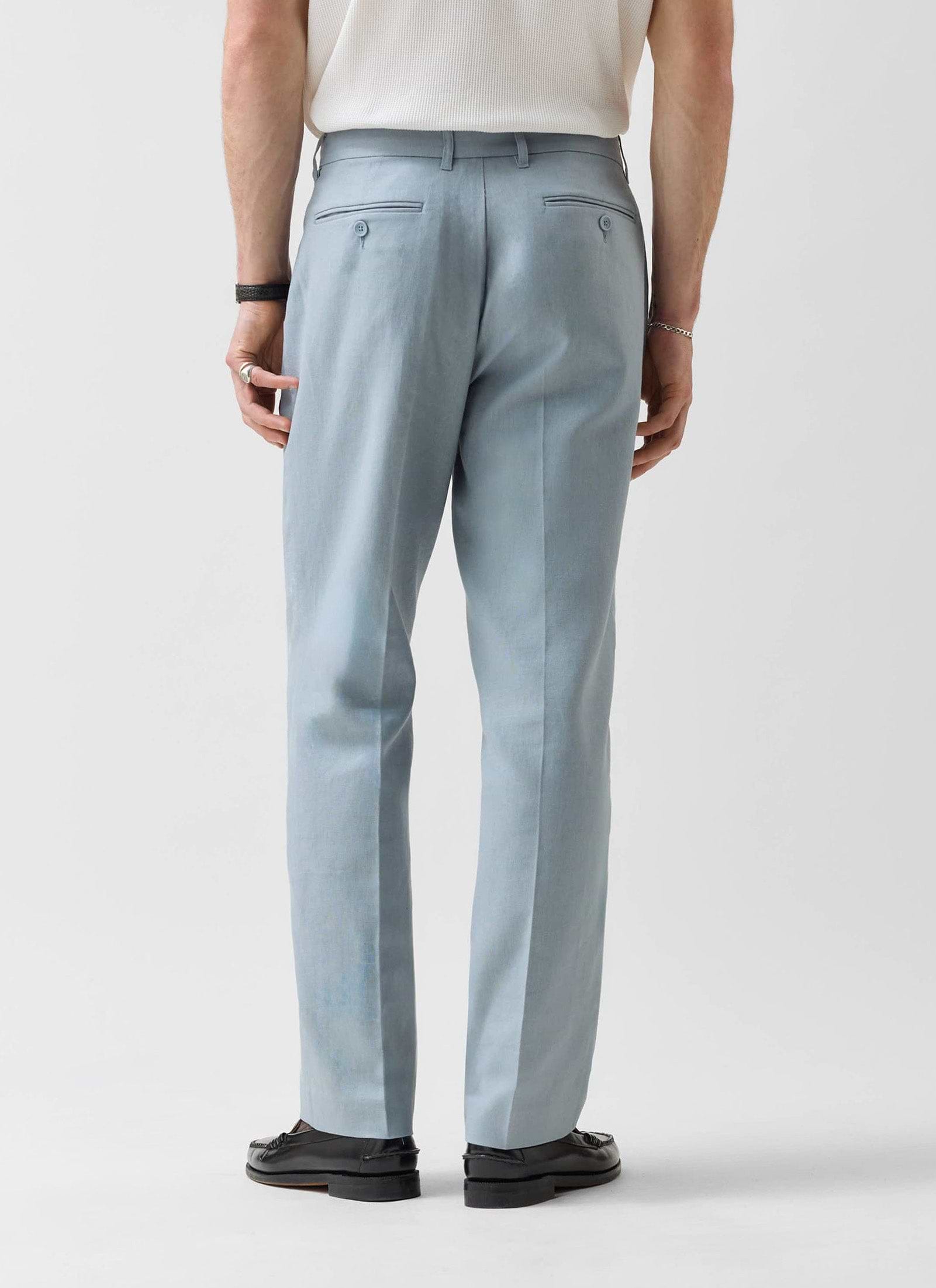 Rear view of a model wearing Percival's light blue tailored linen trousers, showing the straight leg fit and pocket detail.