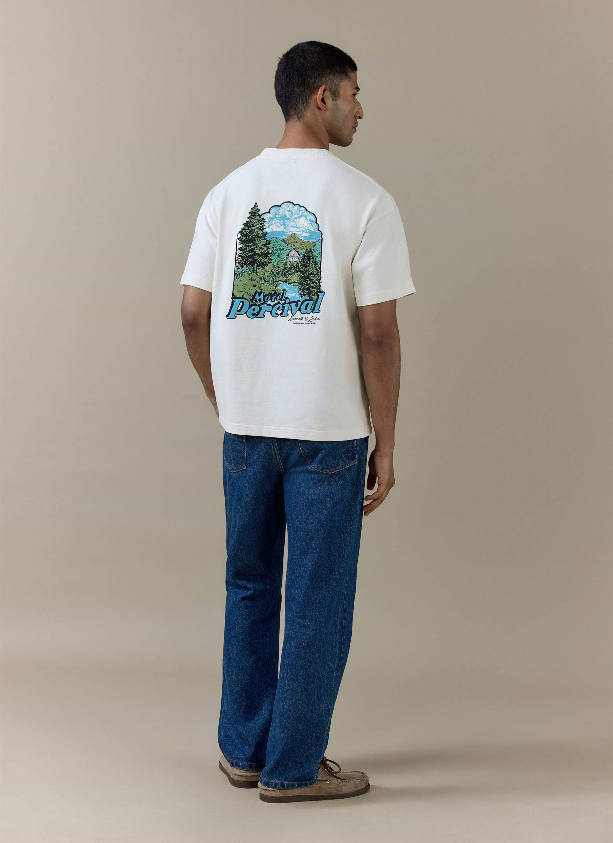 Rear view of the Percival Arnold oversized cream organic cotton t-shirt with a colourful motel landscape back graphic.