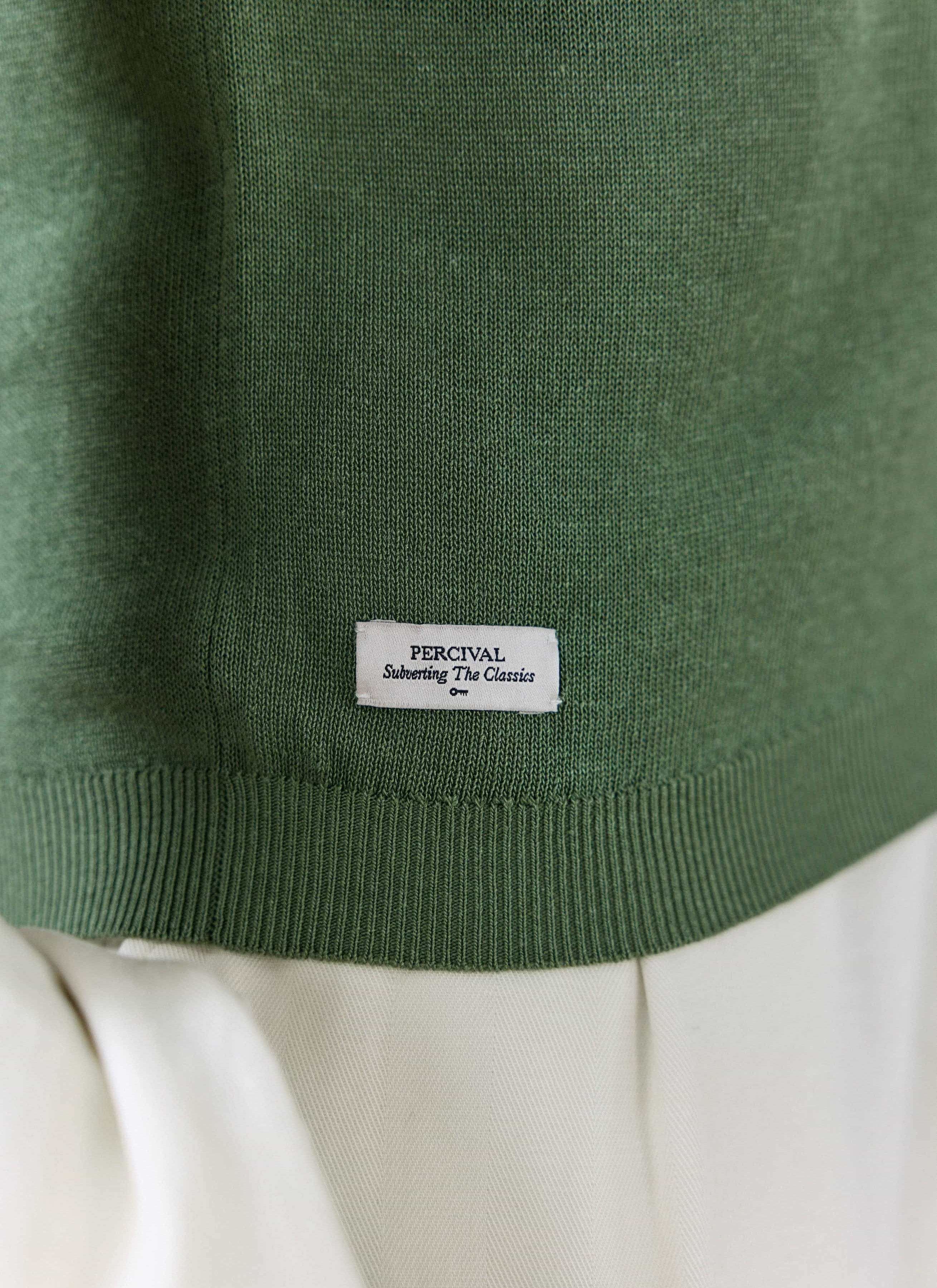 Close-up of the forest green Percival Laurence Knitted Polo in linen lyocell blend, showing fine-gauge knit and hem label.