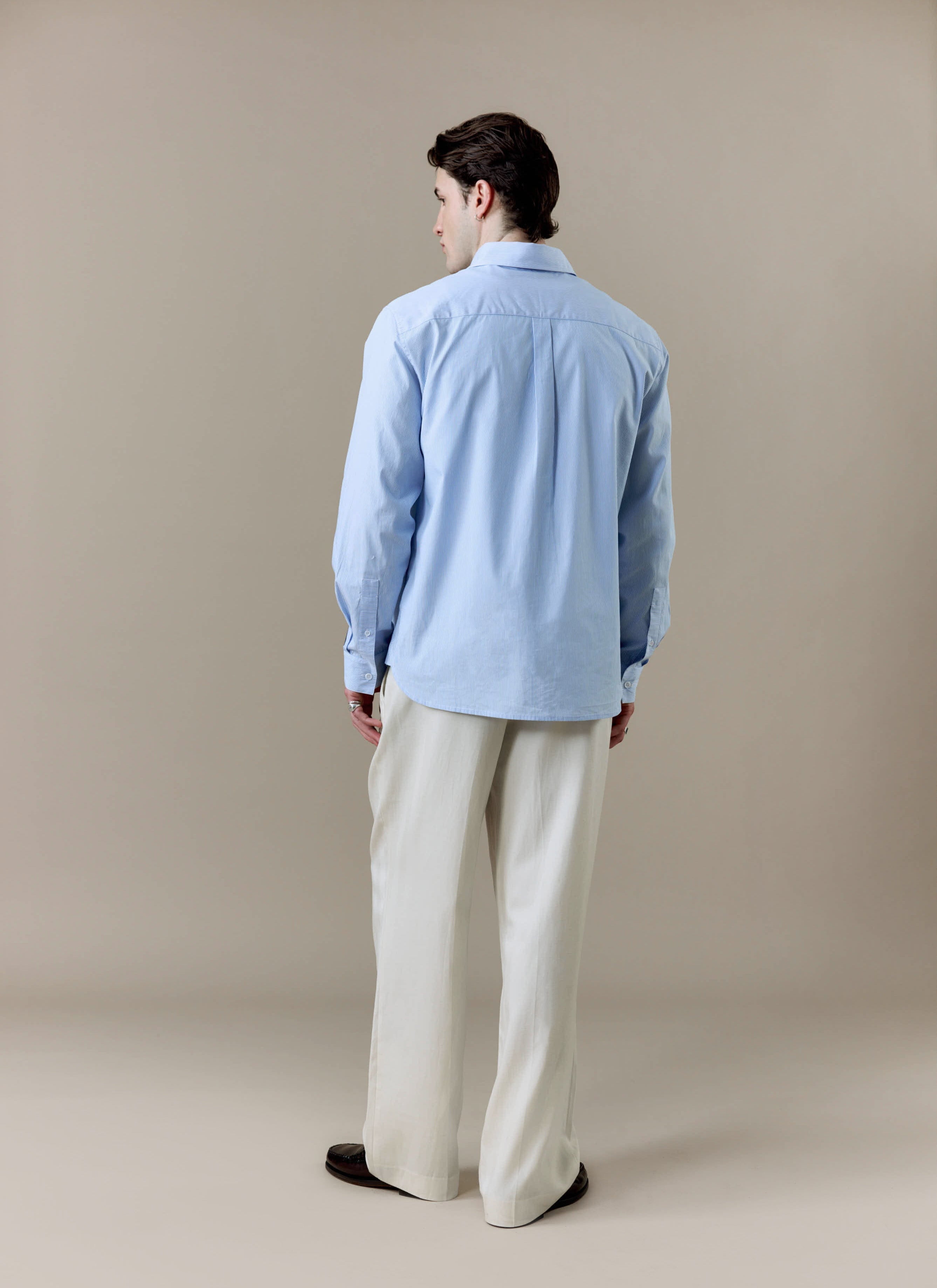 A full-length back view of a model wearing the Percival x Brighton & Hove Albion F.C. Striped Pearce Long Sleeve Shirt.