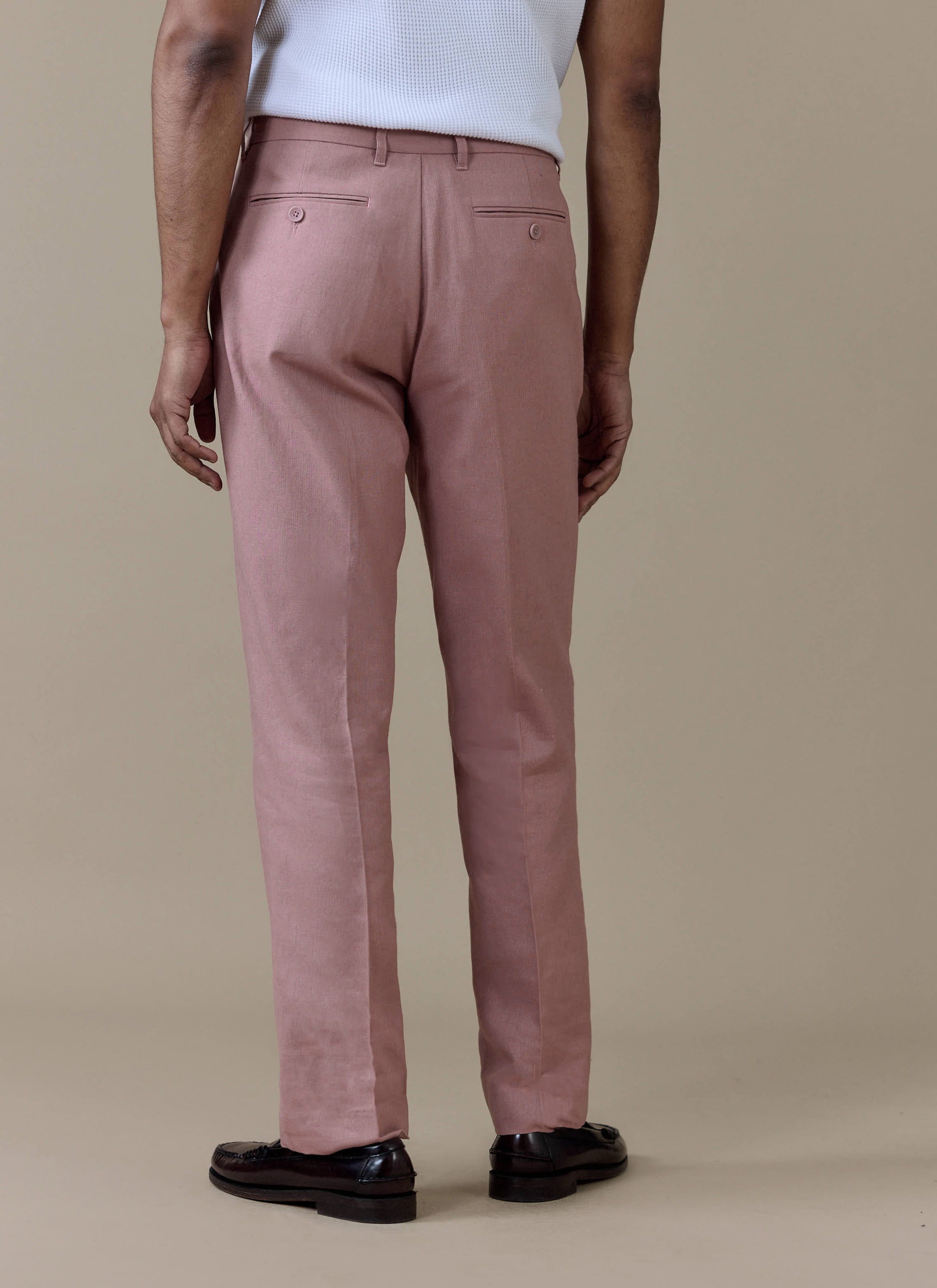 Dusty pink Percival Tailored Linen Trousers shown from behind, featuring buttoned welt pockets and a sharp centre crease.