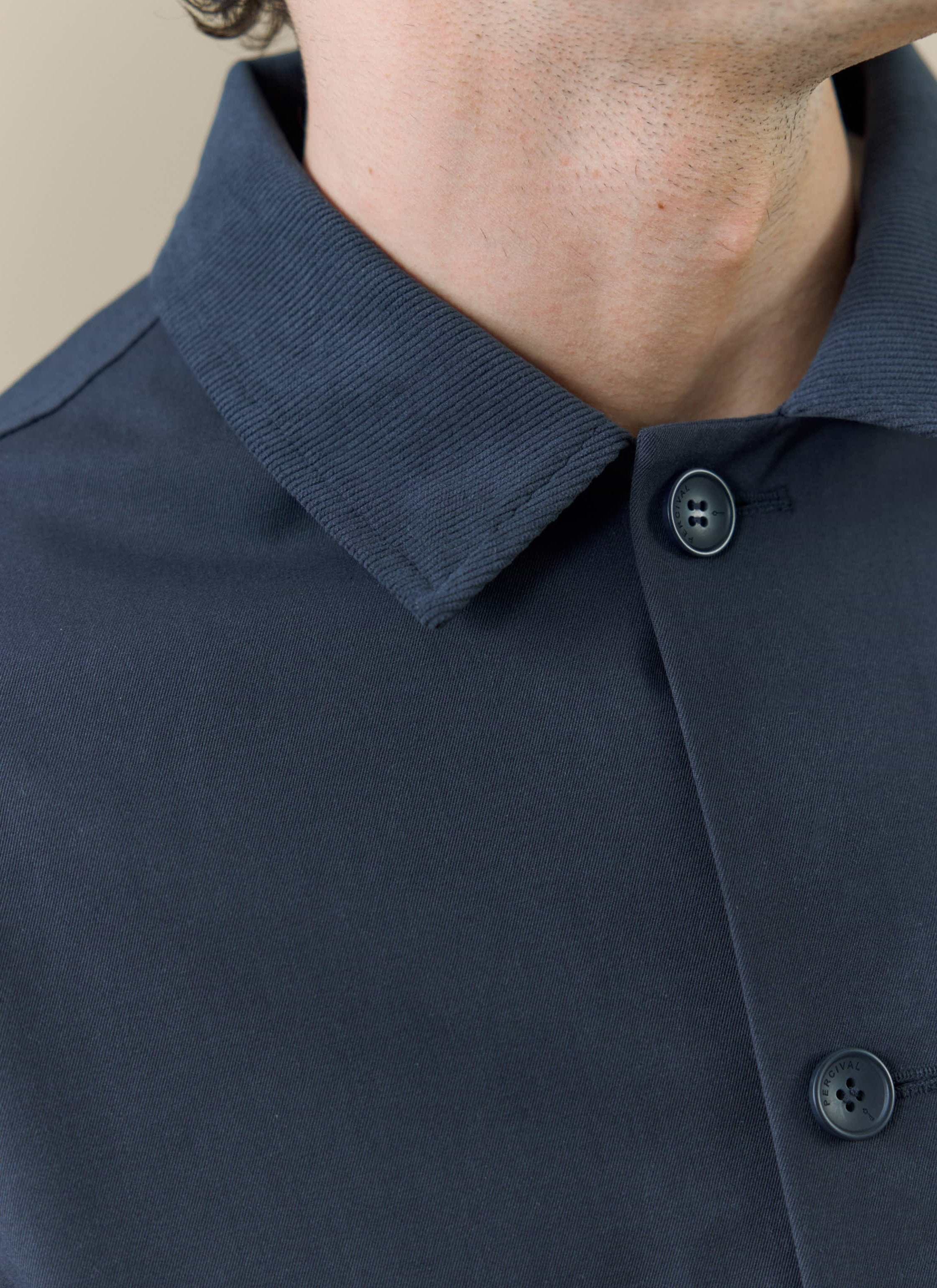 A close-up of the Percival Sherlock Trench in midnight, showing the ribbed collar and branded button detail.