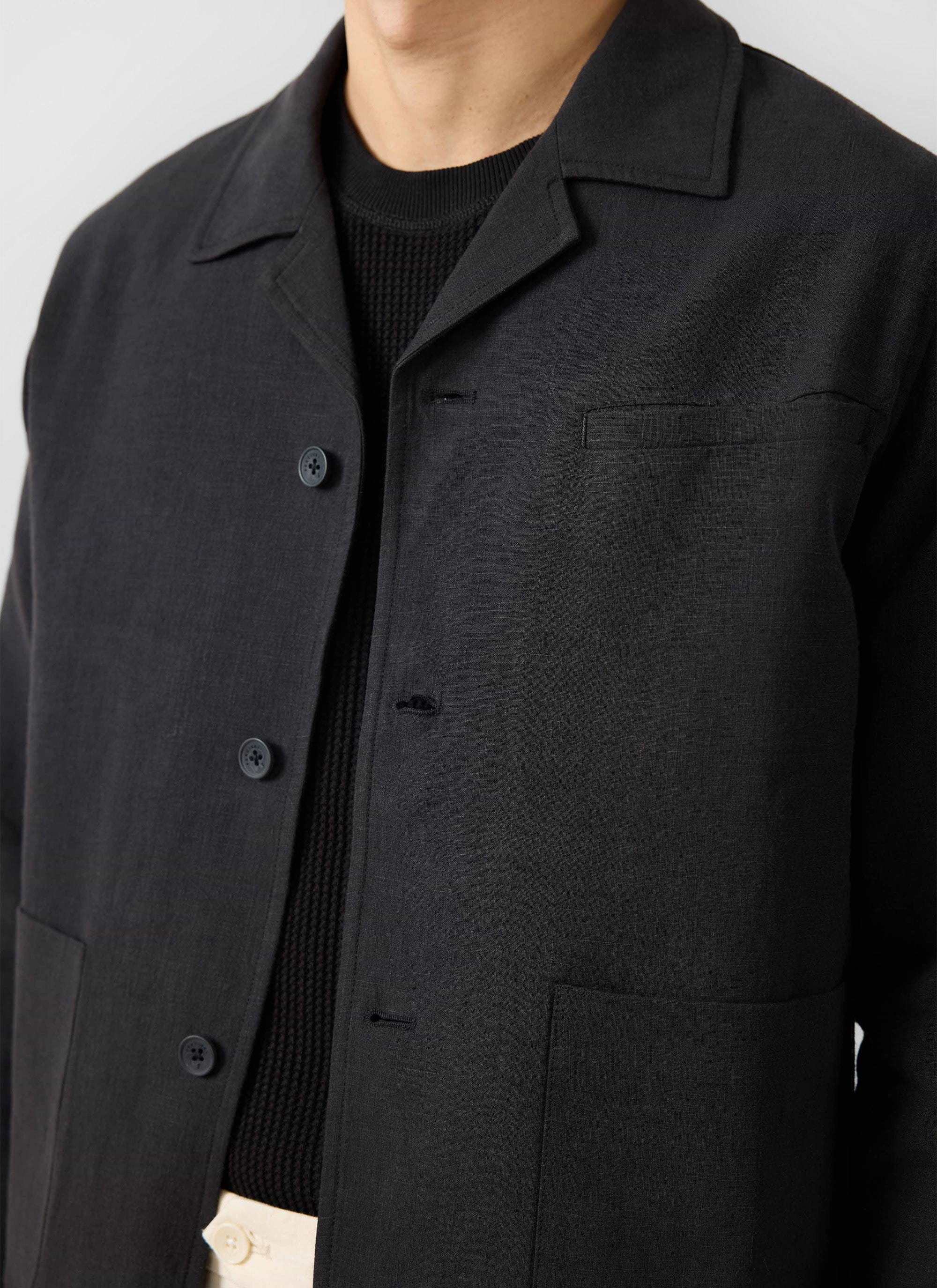 A close-up of a model wearing the Percival black linen overshirt, showing the collar and chest pocket detail.