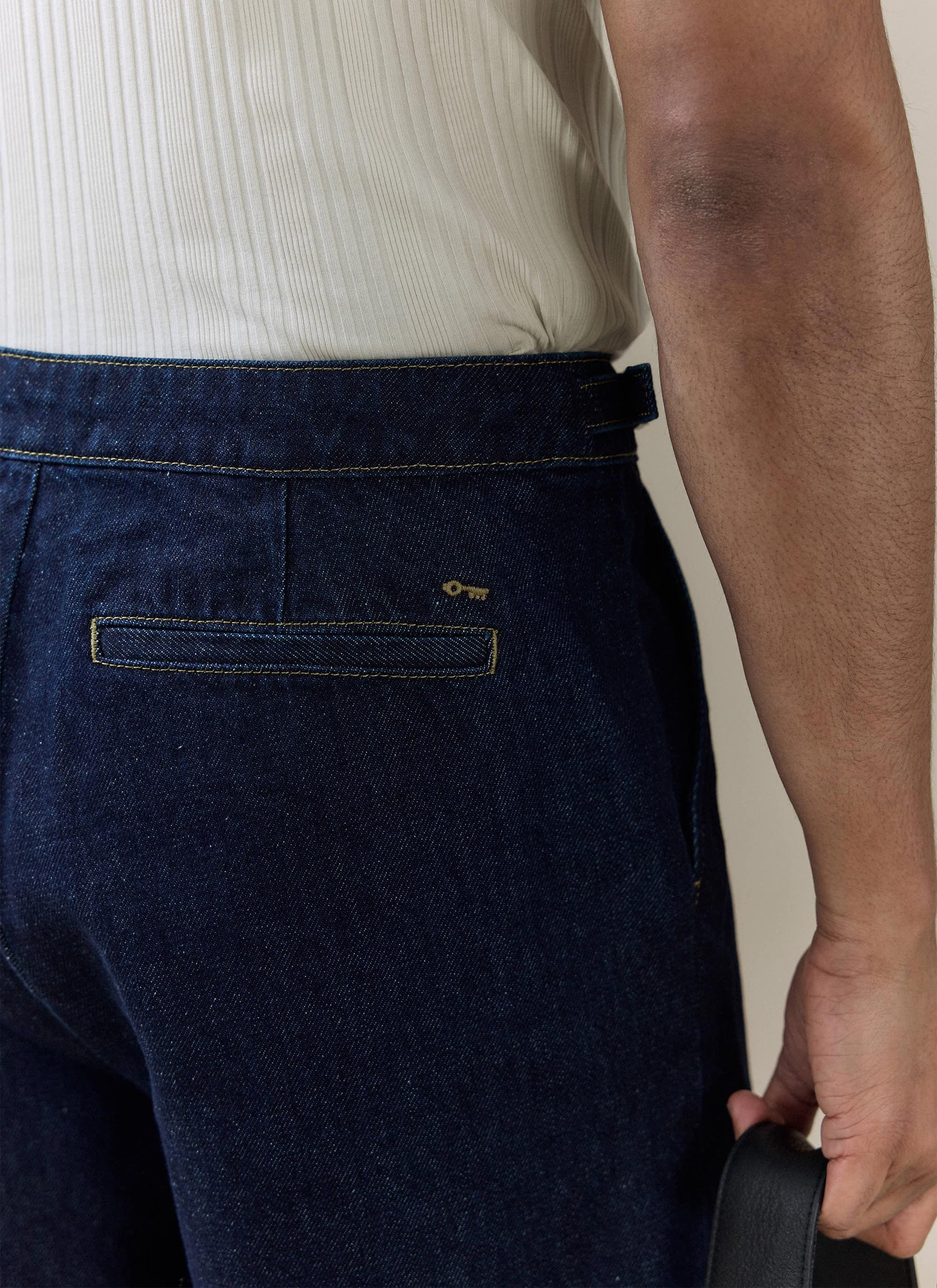 Percival Blake Double Pleated Denim Shorts in dark indigo, featuring an embroidered key logo and contrast-stitched pocket.