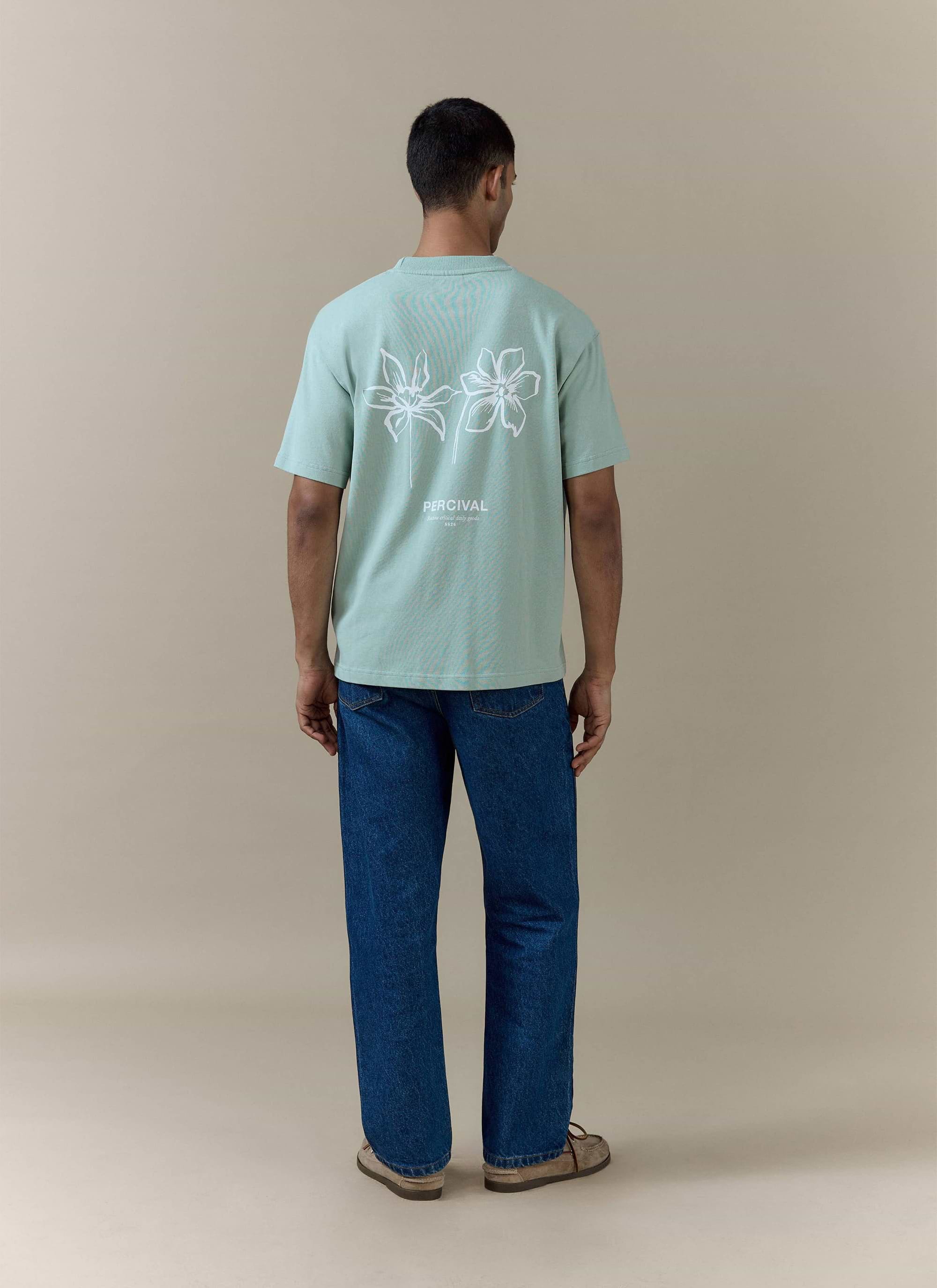 Rear view of the Percival Melvin Oversized T Shirt in sage organic cotton, featuring a white floral back graphic.