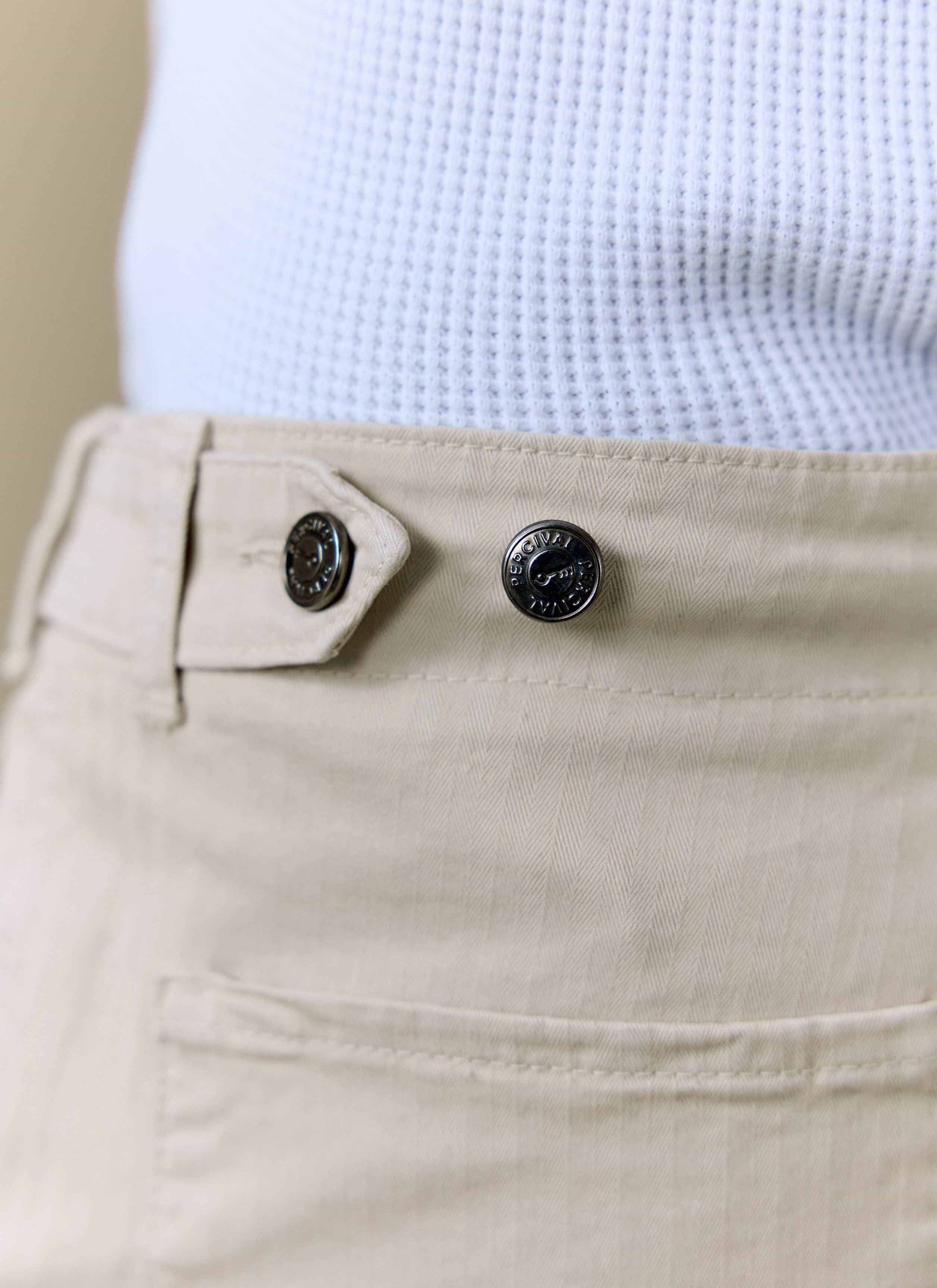 Detail of the Percival Lungo Herringbone Straight Trousers in cream, showing the branded waist buttons and fabric texture.