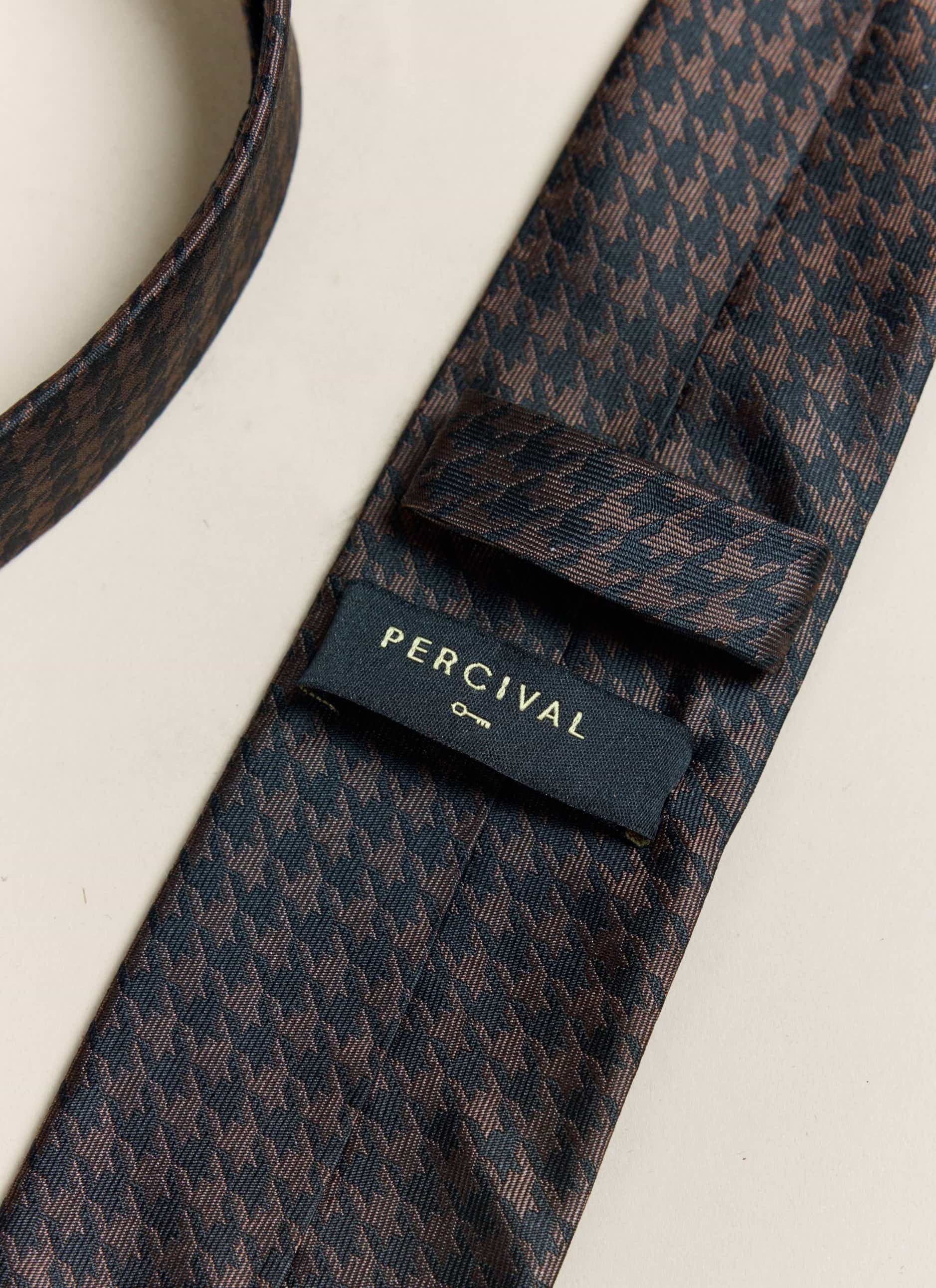 A close-up of the reverse of the Percival brown houndstooth silk tie, showing the brand label and keeper loop.