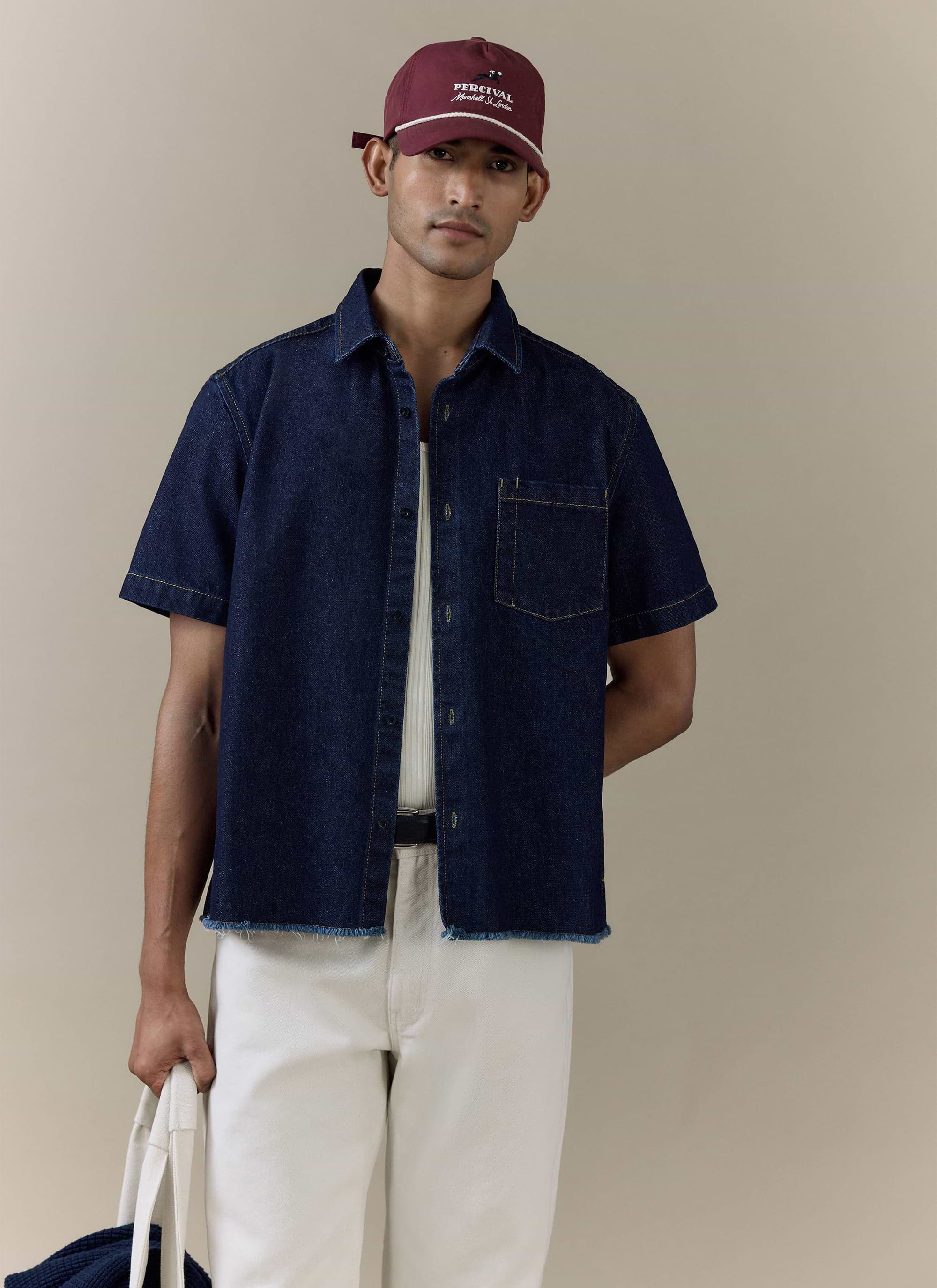 Model wearing the Percival Harley Denim Cropped Boxy Shirt in dark indigo cotton, featuring a raw, frayed hem.