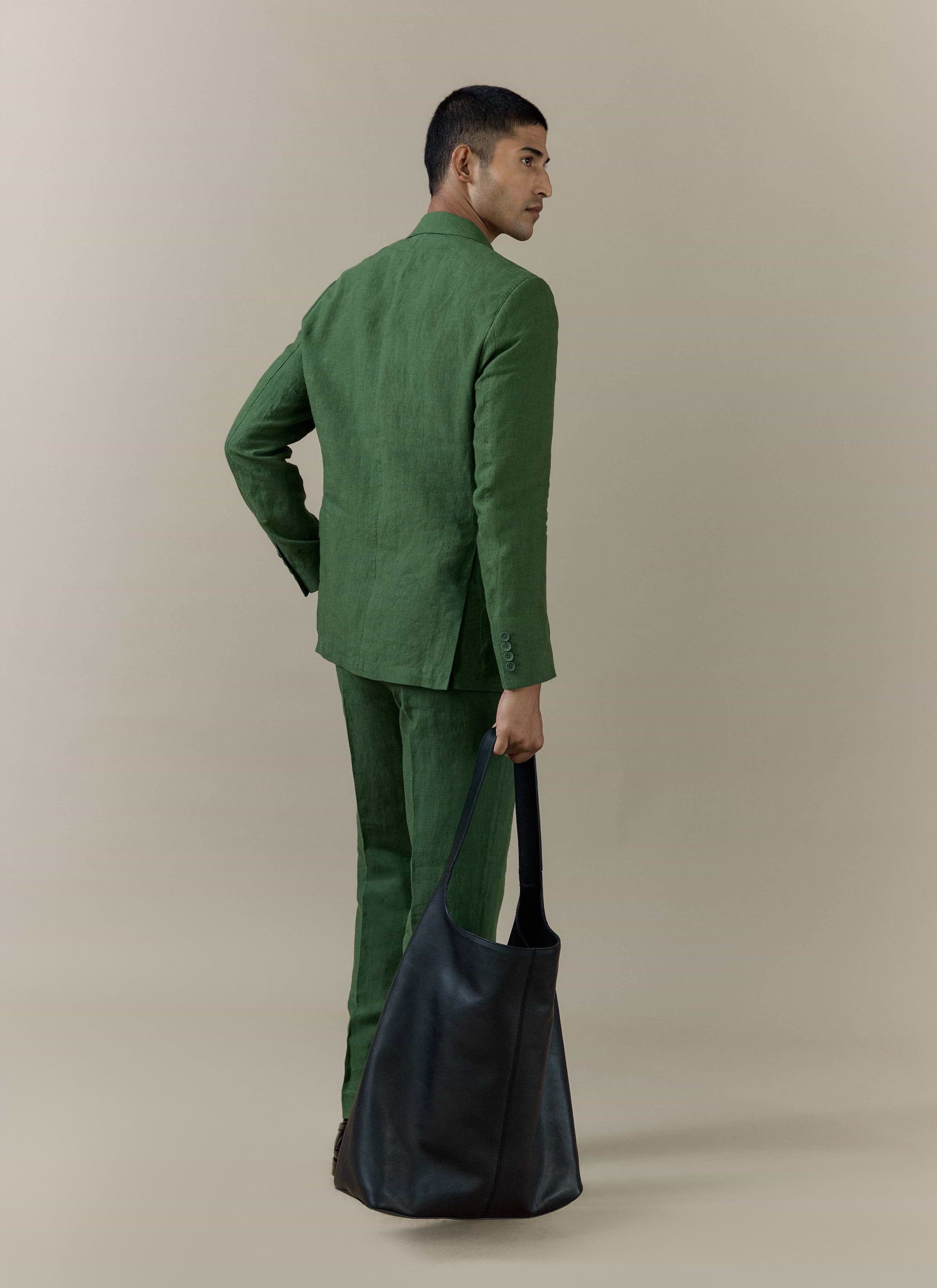 Rear view of the Percival slim fit classic blazer and trousers in forest green linen, paired with a large black bag.