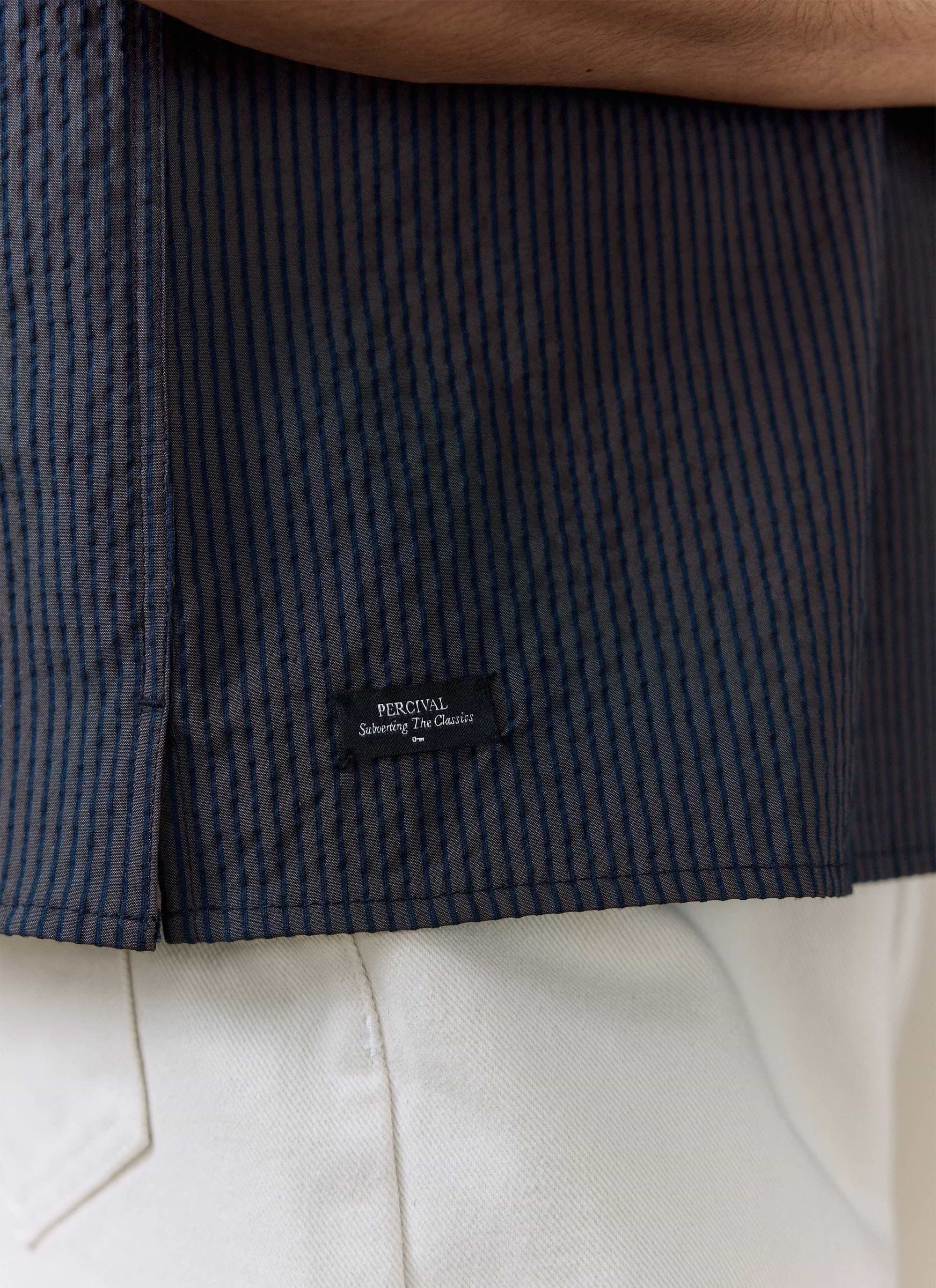 Close-up of the navy stripe seersucker cotton on the Percival Rowan Boxy Shirt, featuring the woven brand label.
