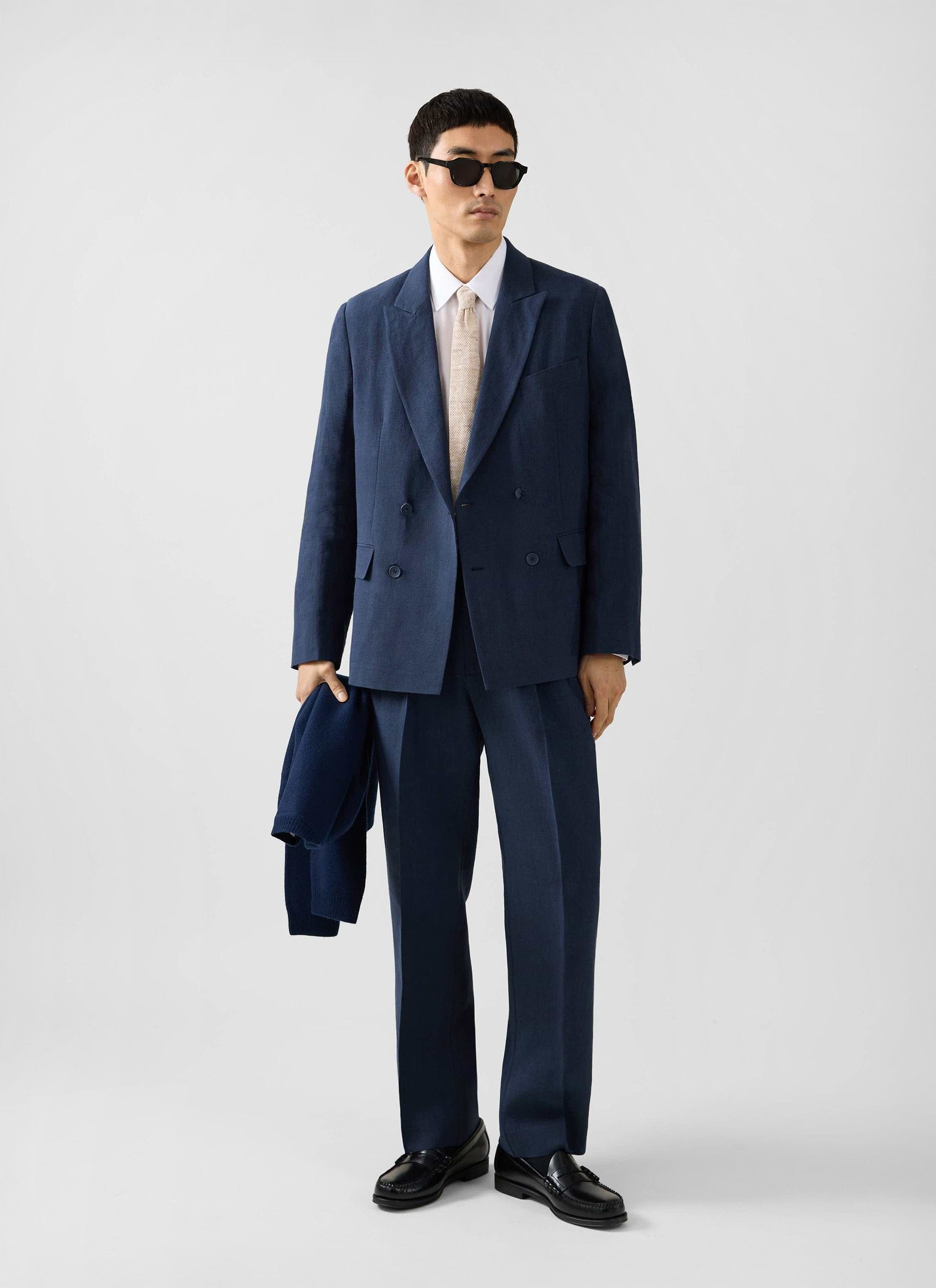 A model wears the Percival Clifton Double Breasted Blazer and matching trousers in navy linen, styled with sunglasses.