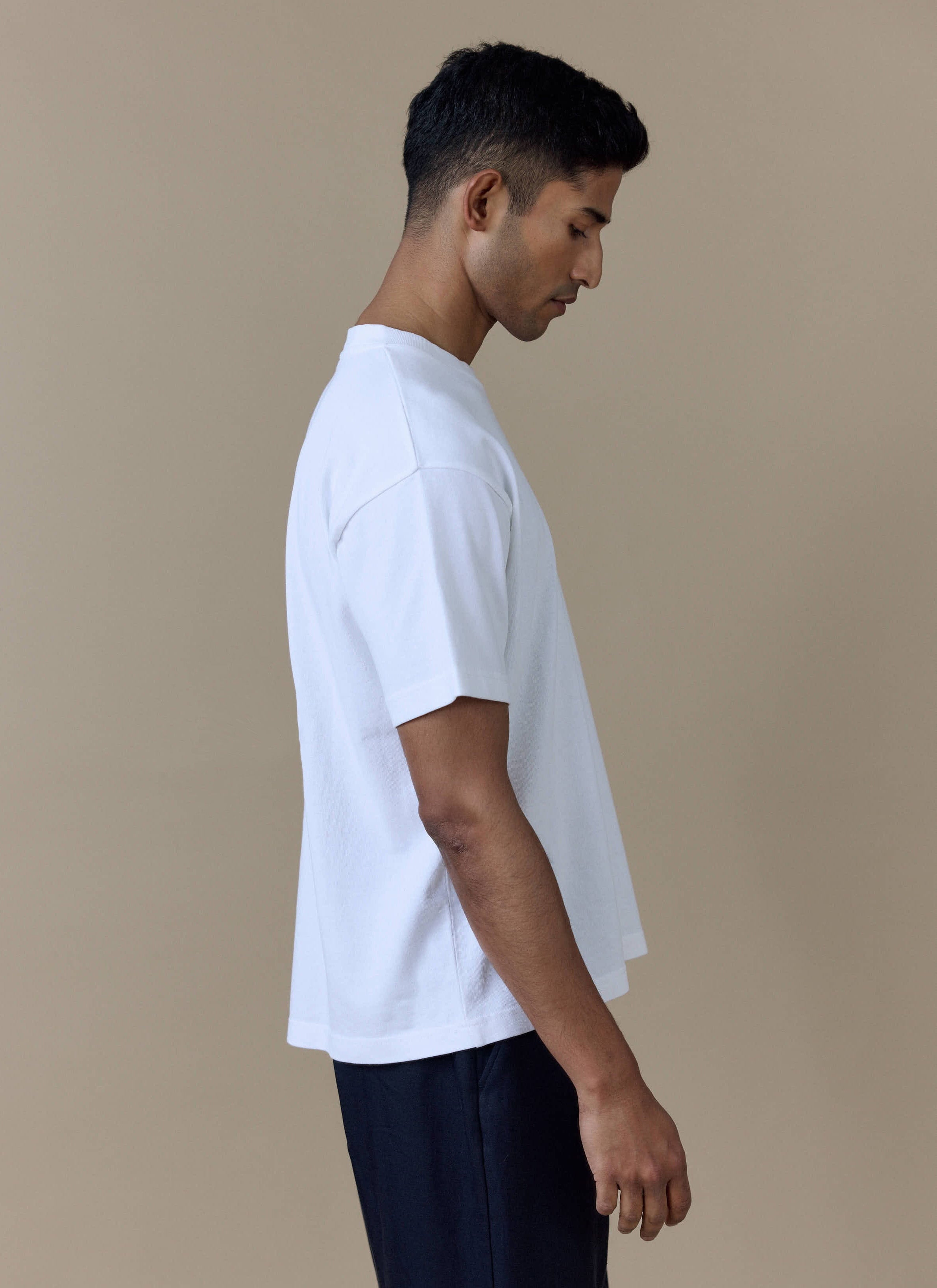 Side view of a model wearing the white Guinness x Percival Printed Oversized T-Shirt.