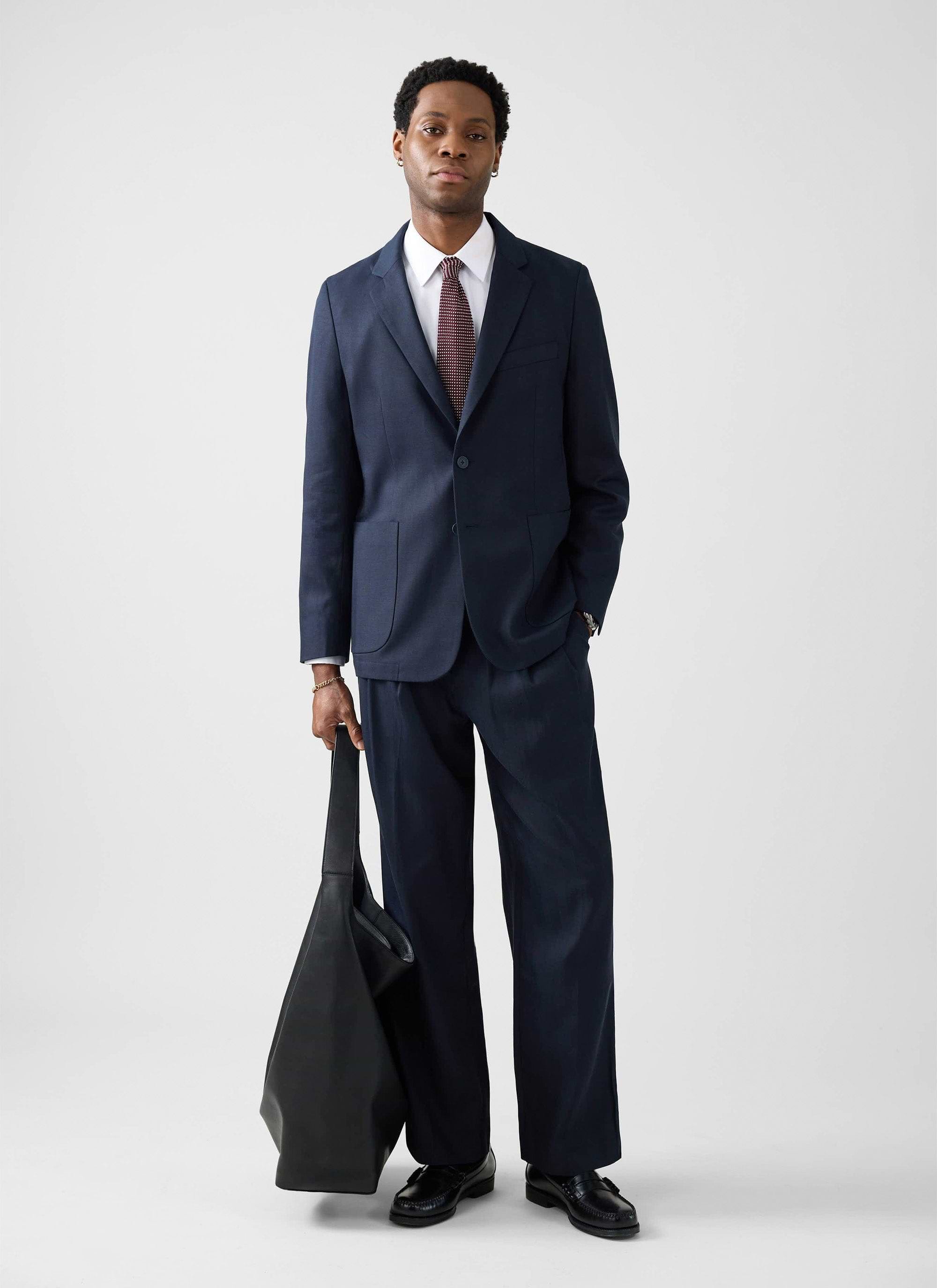 A model wears the navy Lyocell Regular Blazer and matching trousers from Percival, styled with a shirt and tie.