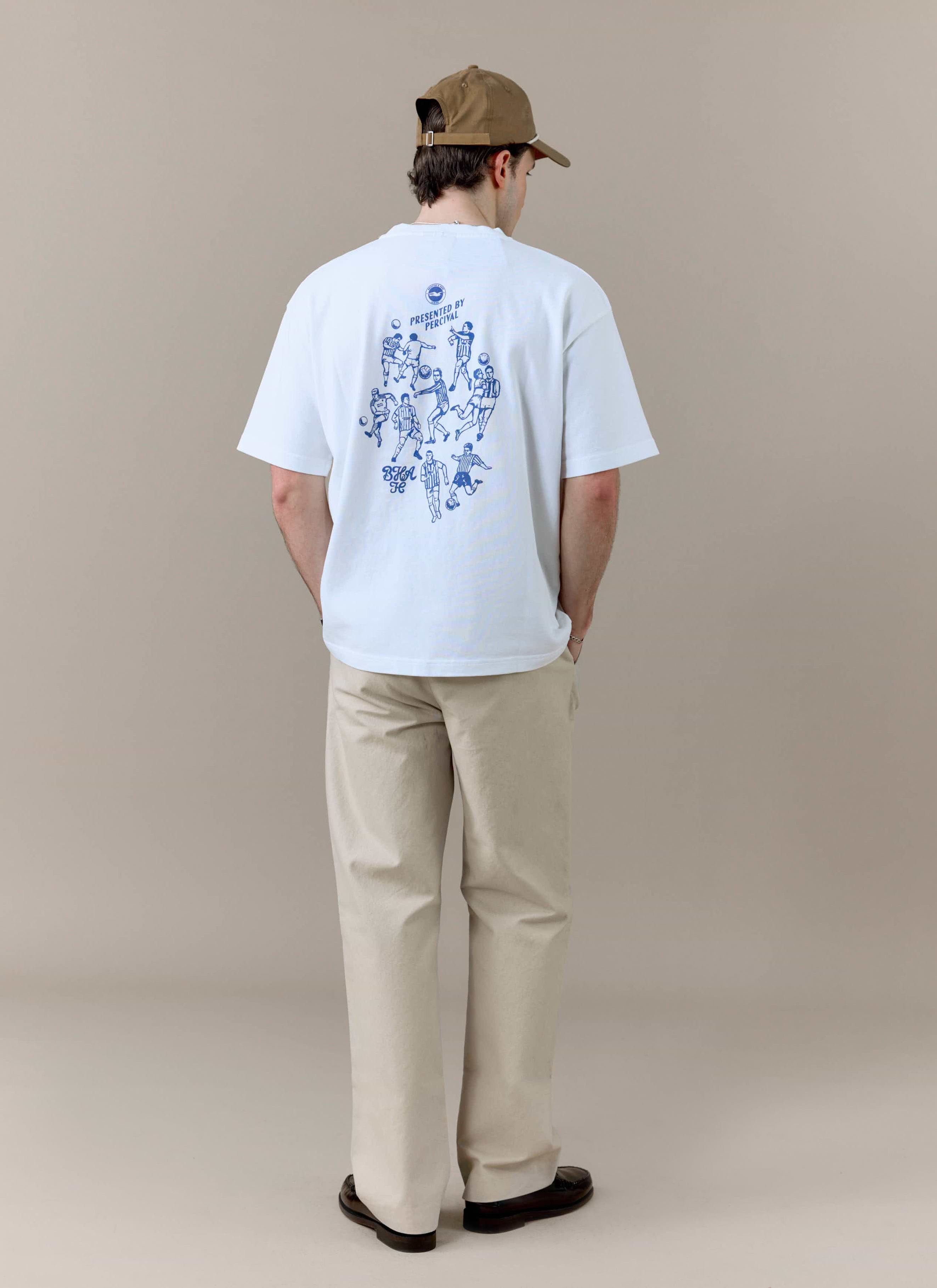 A model wears the white Percival x Brighton & Hove Albion F.C. t-shirt, showing the blue football graphic on the back.