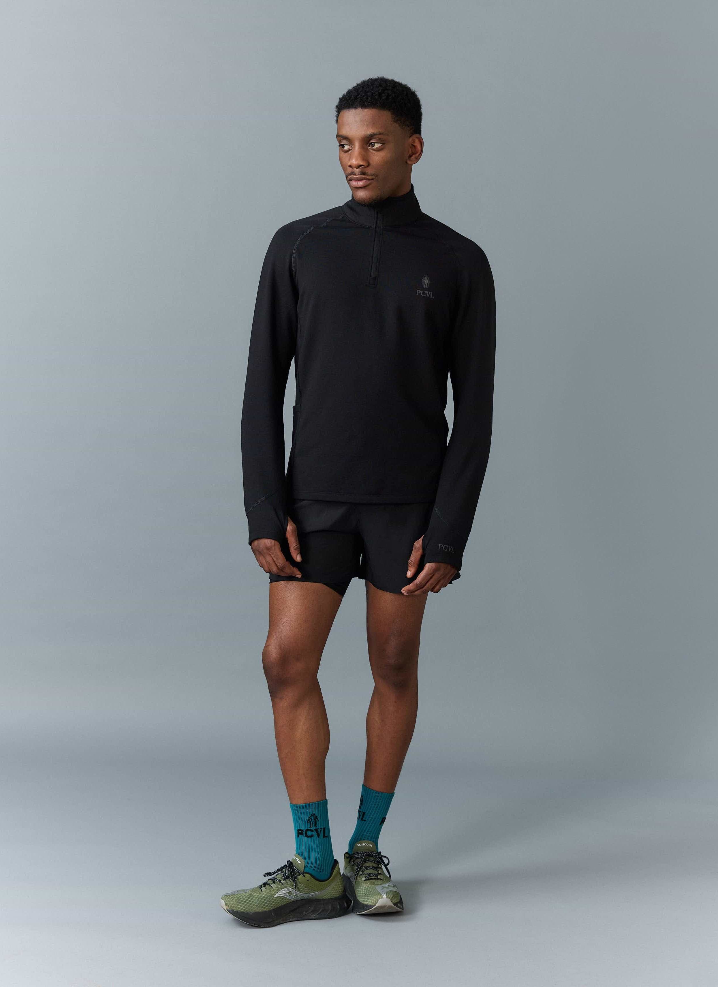 Full length shot of a male model wearing the black PCVL Base Layer Quarter Zip jacket from Percival.