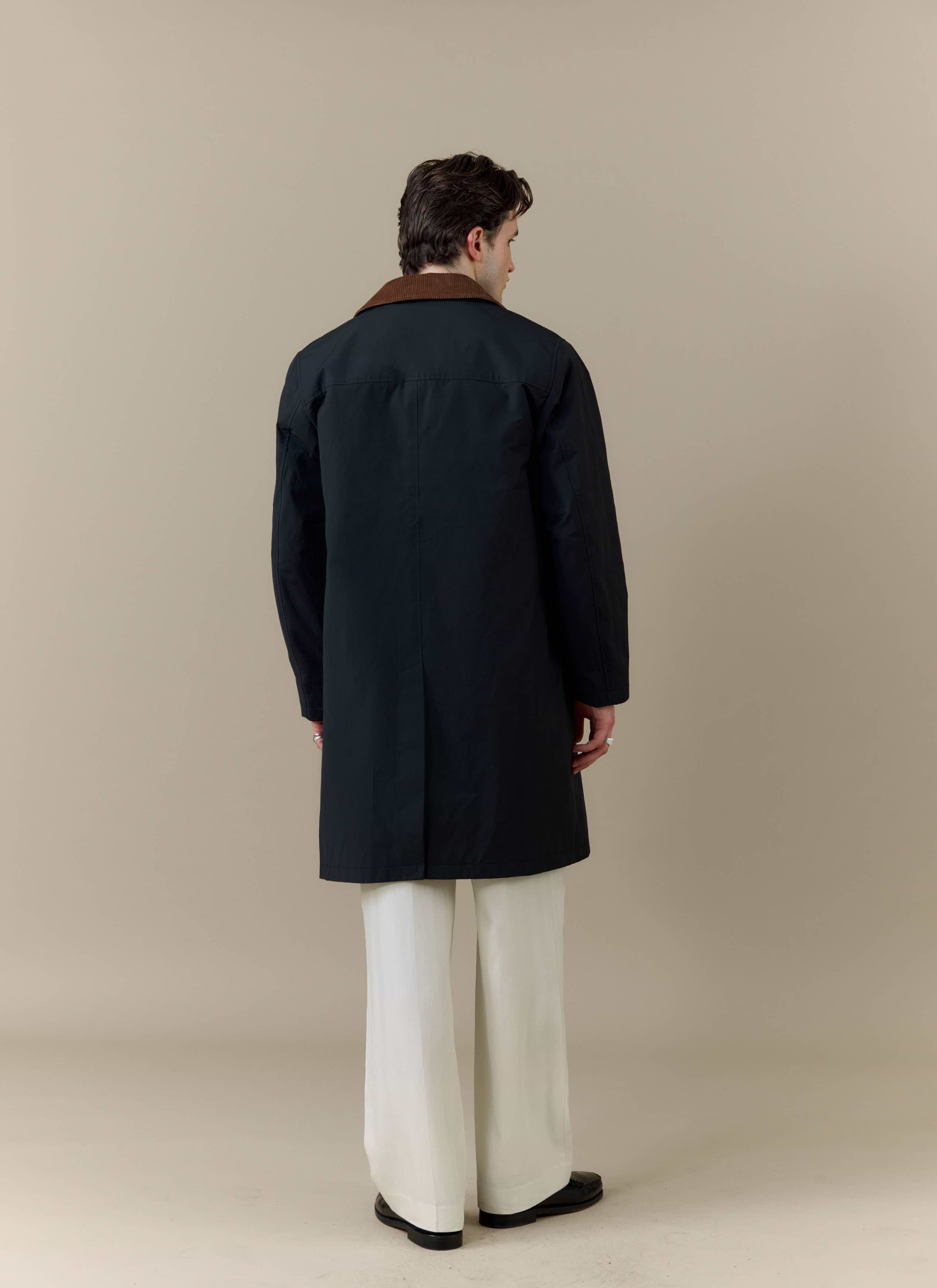Back view of a model wearing the Percival Cord Collar Relaxed Trench Coat in black with a brown corduroy collar.
