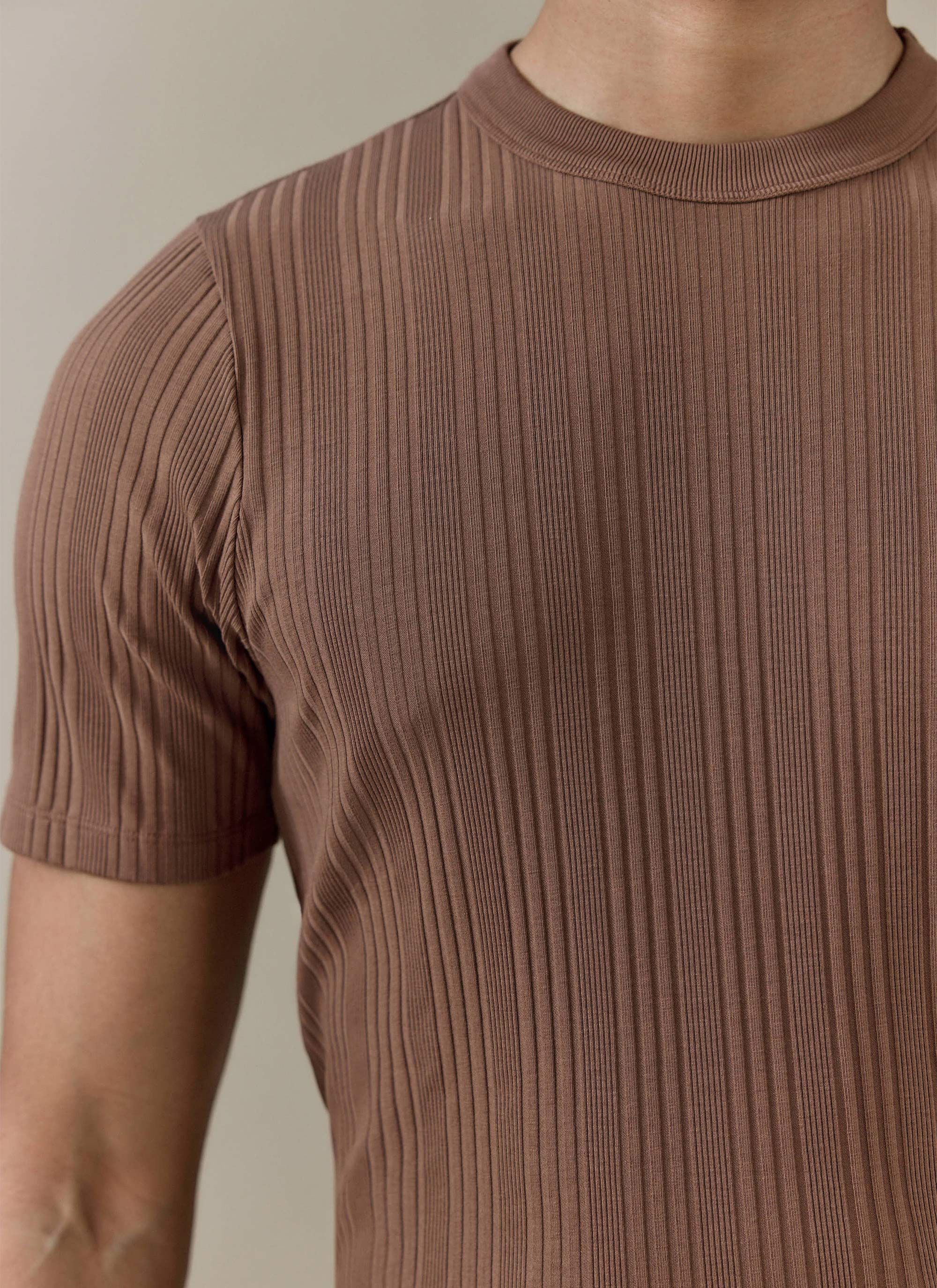 A close-up of the brown Percival Leon Ribbed T-Shirt, showing the vertical rib texture and organic cotton material.