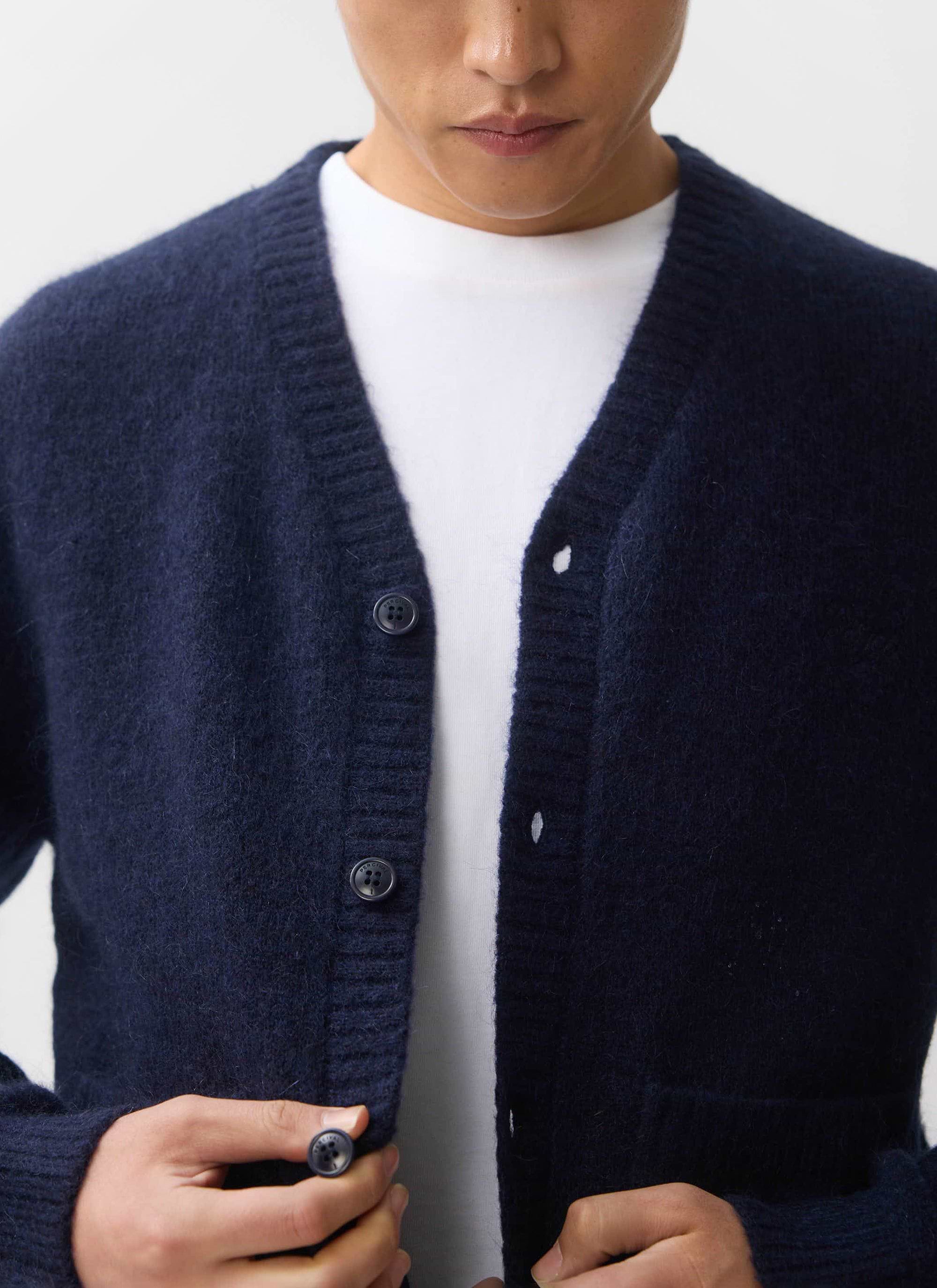 A close-up of a man wearing the Percival White Glove Cardigan in navy mohair, layered over a classic white t-shirt.