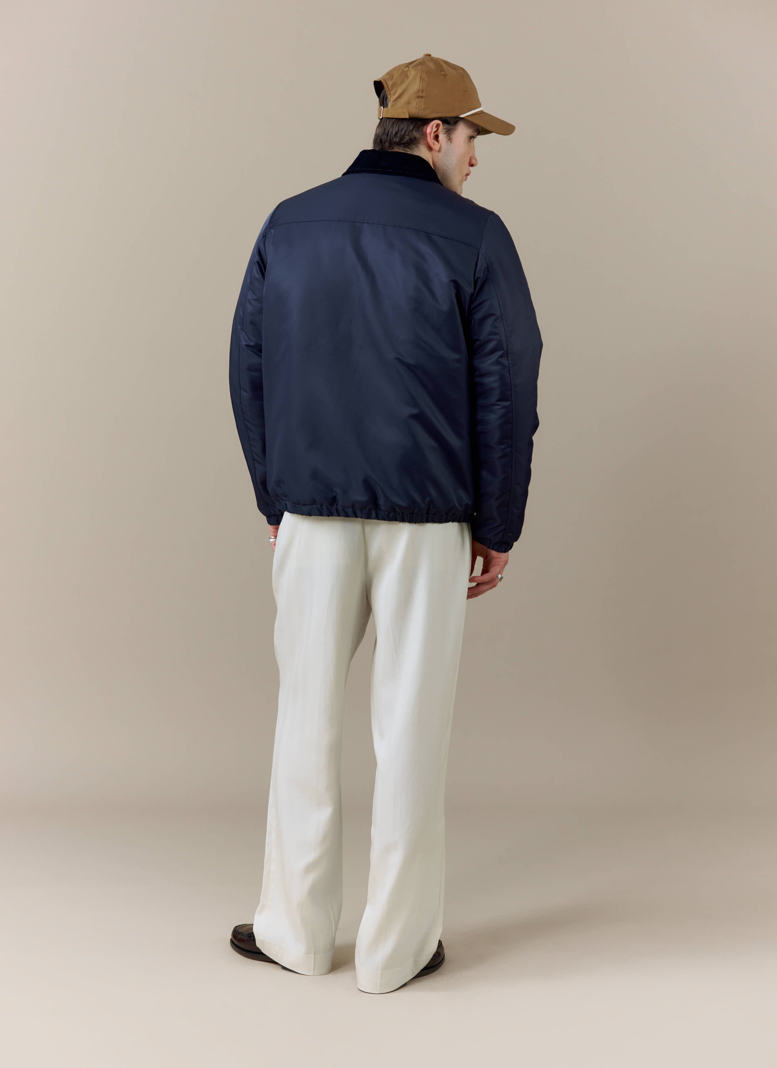 Back view of a model styled in the navy Coach Jacket from the Percival x Brighton & Hove Albion F.C. collaboration.