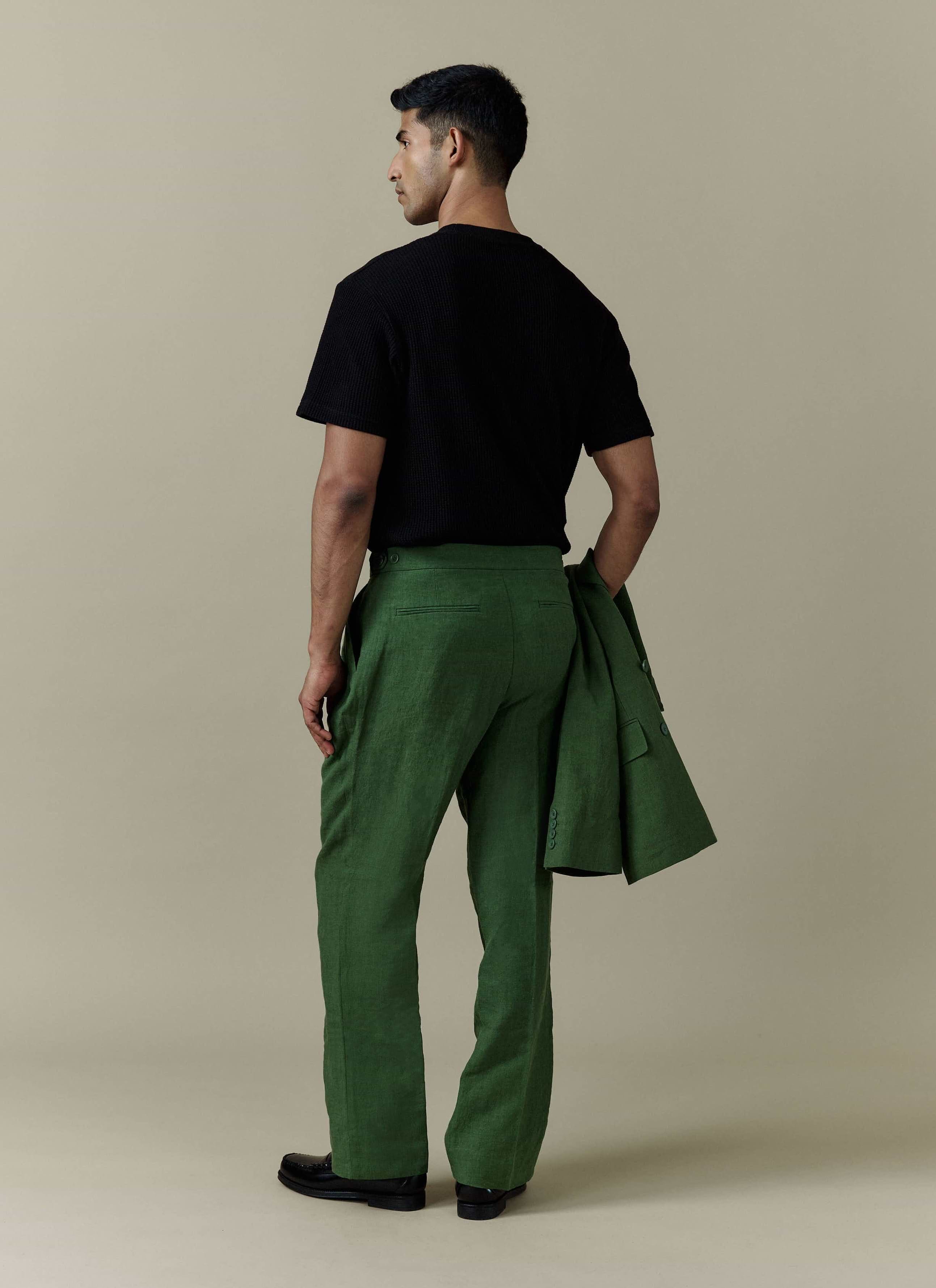A model from behind in Percival forest green pleated linen trousers, holding a matching tailored linen blazer.