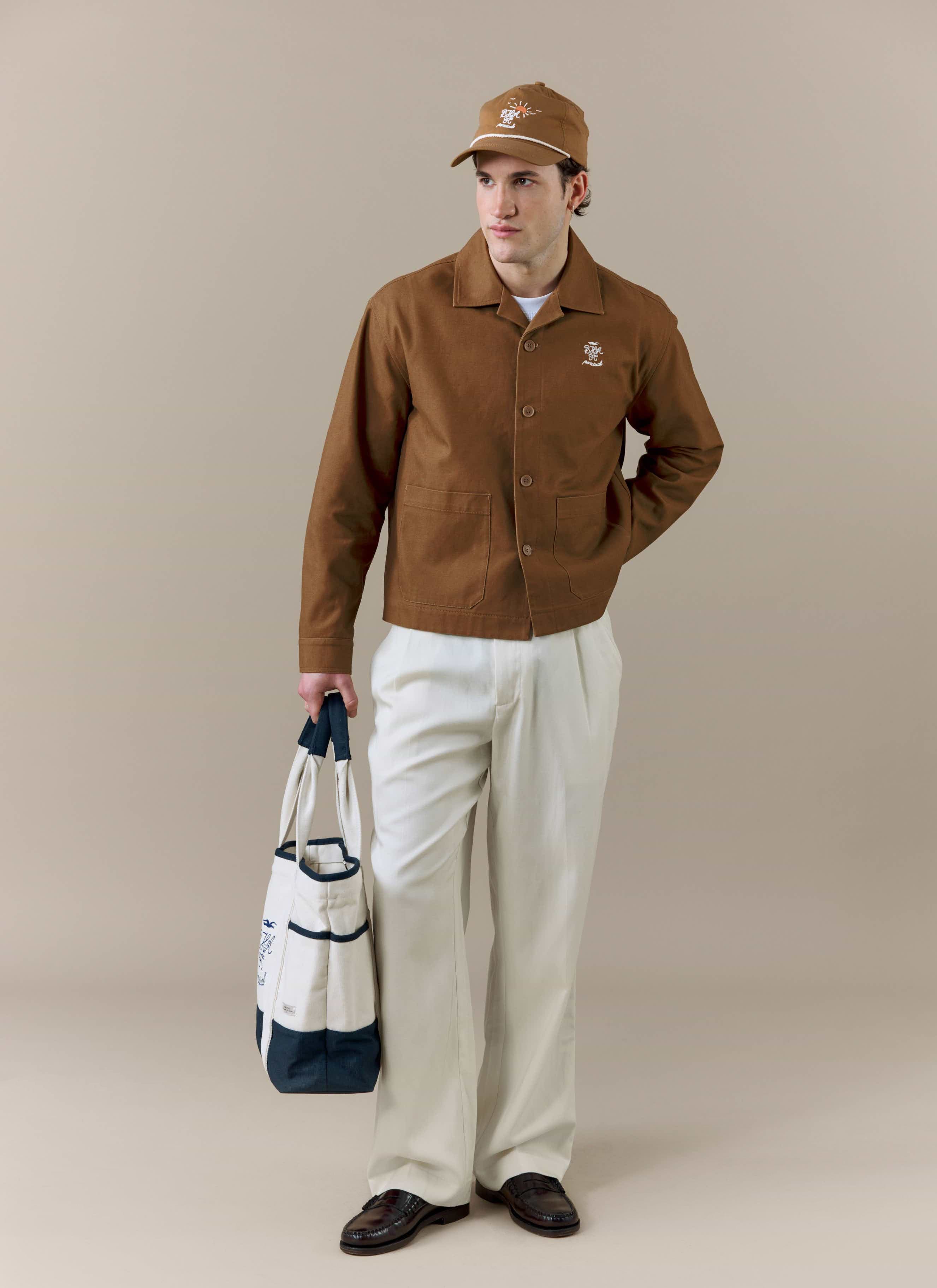 A full-length shot of a model wearing the brown Canvas Workshirt from the Percival x Brighton & Hove Albion F.C. collection.