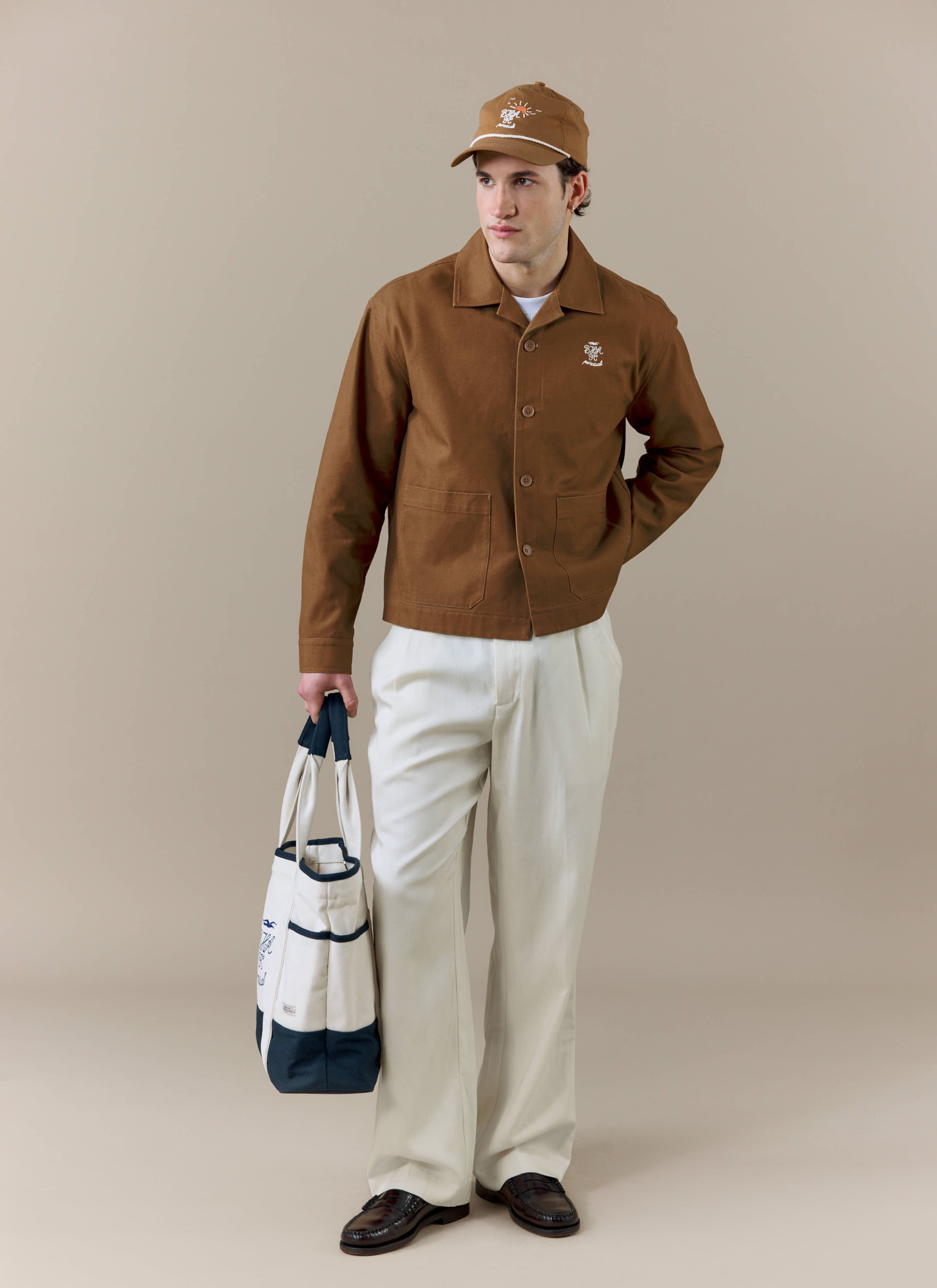 A full-length shot of a model wearing the brown Canvas Workshirt from the Percival x Brighton & Hove Albion F.C. collection.