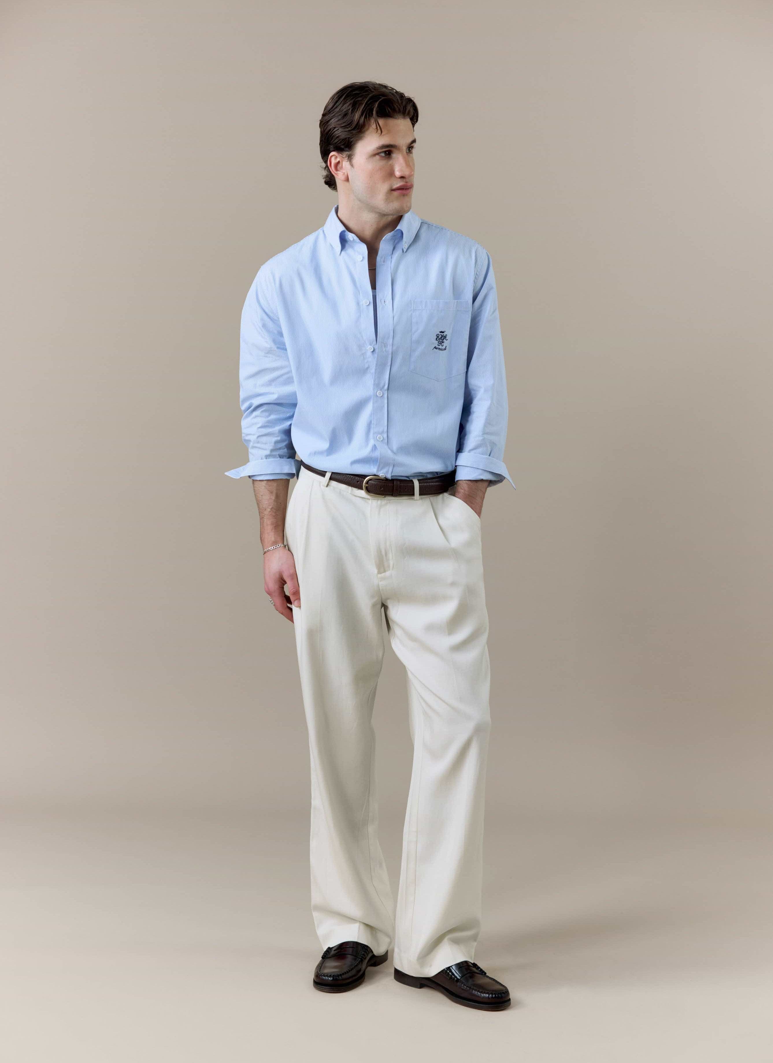 A model wears the blue and white striped Pearce Long Sleeve Shirt from Percival, styled with white trousers and loafers.