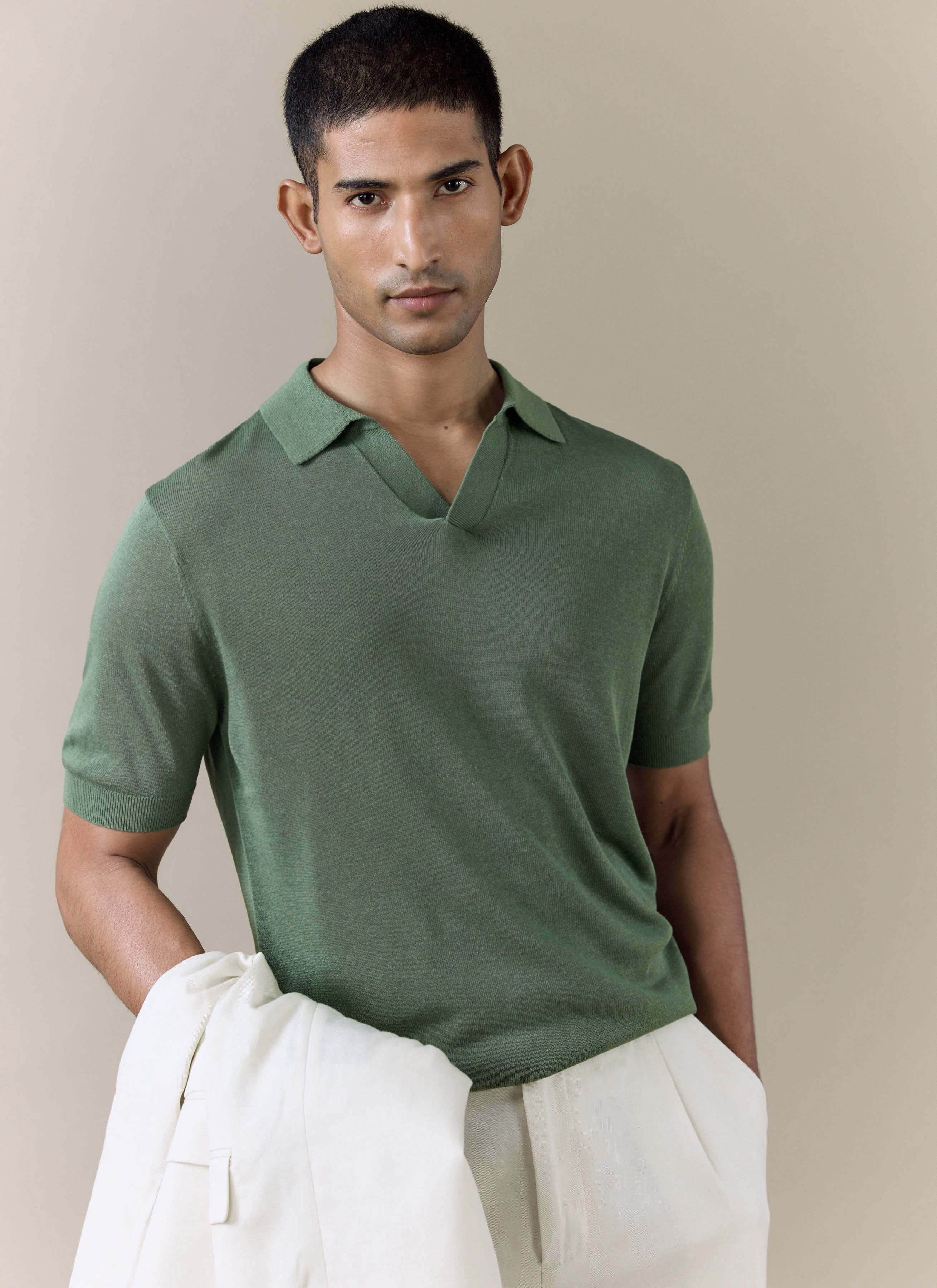 Model wearing the forest green Percival Laurence knitted polo, a breathable linen blend piece with an open V collar.