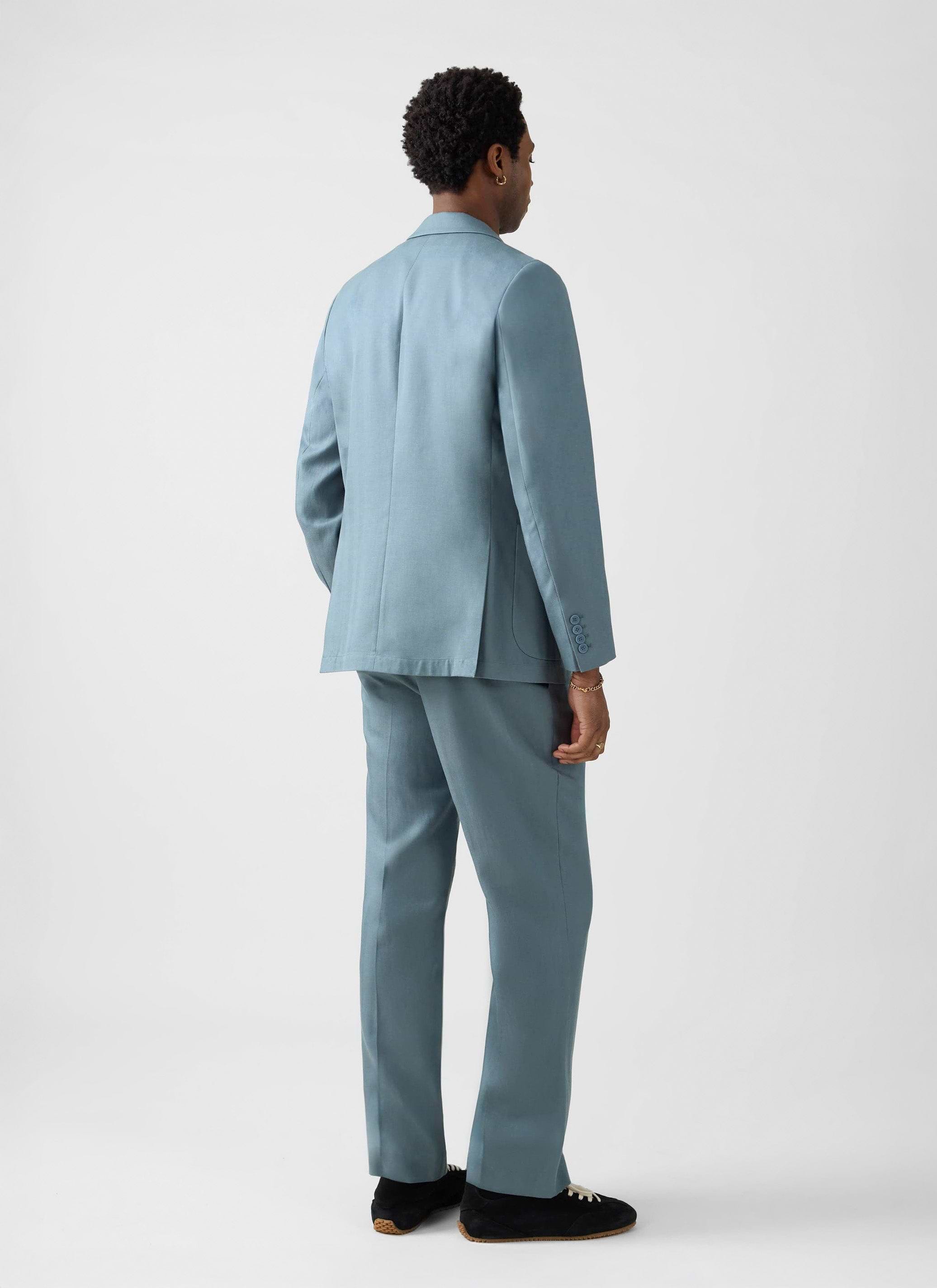 A model from behind wearing the Percival Lyocell Regular Blazer and matching suit trousers in slate blue.