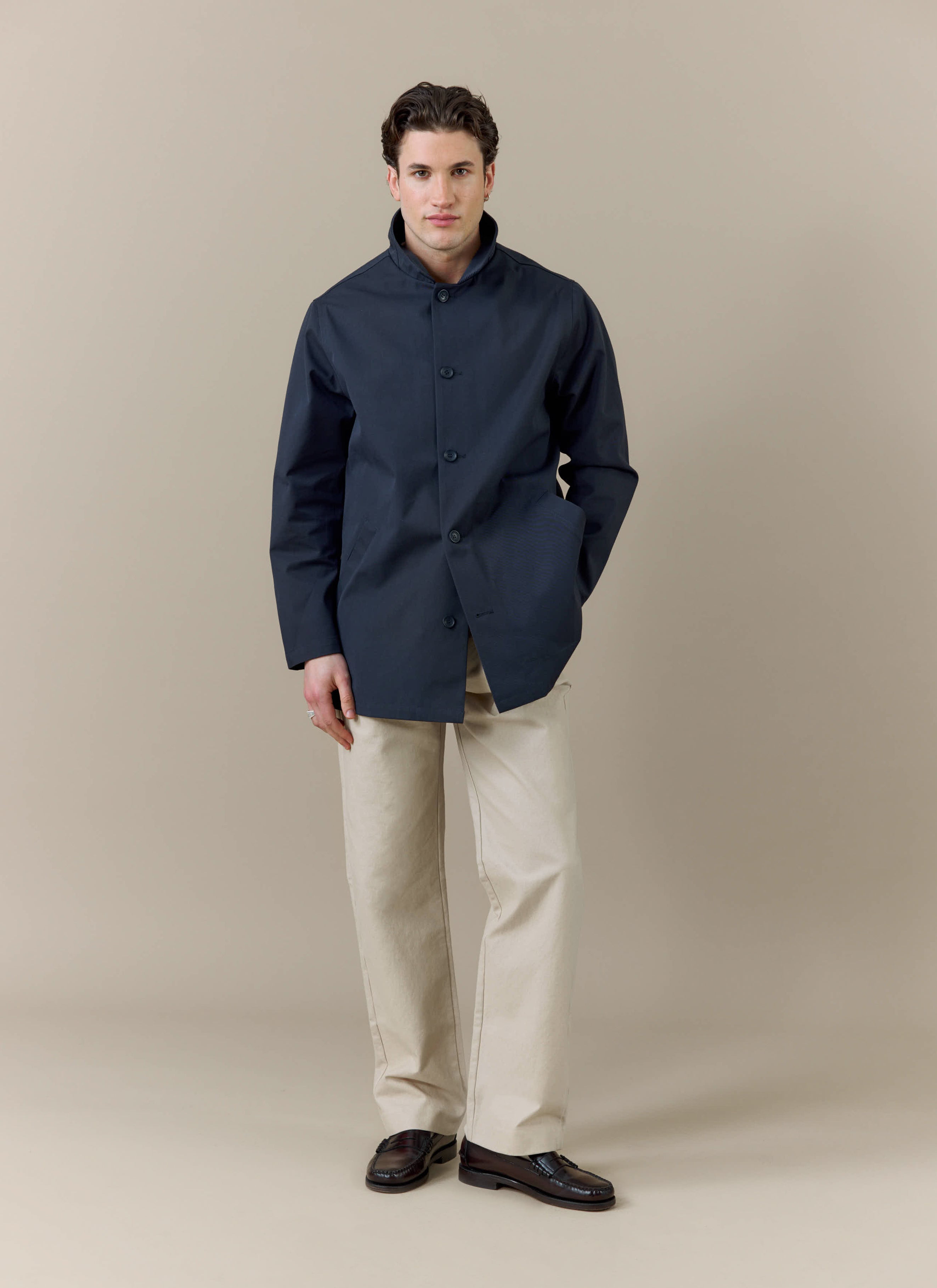 A model wears the Percival x Brighton & Hove Albion F.C. Sherlock Trench in Midnight with Olive against a neutral background.