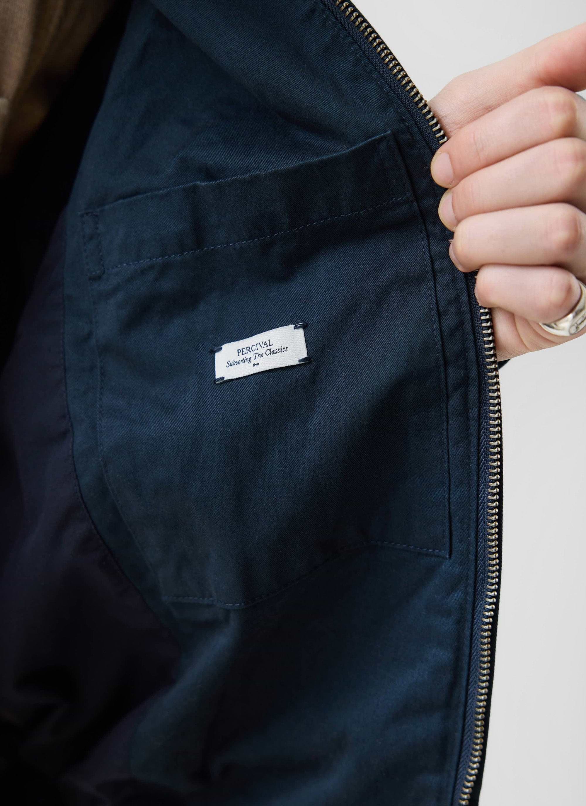 A close-up of the internal pocket and branded label on the navy cotton Leo Harrington Jacket by Percival.