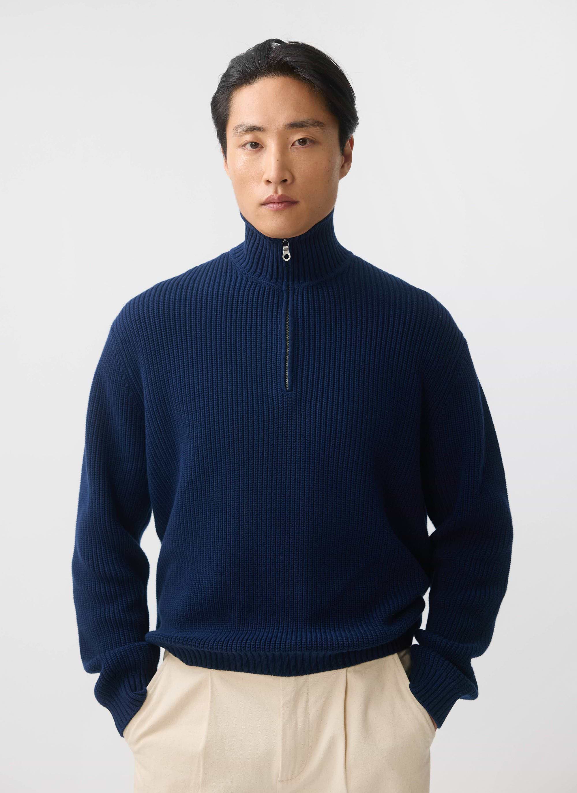 A model wears the Percival Meyer Quarter Zip Fisherman jumper in blue cotton, styled with cream trousers.