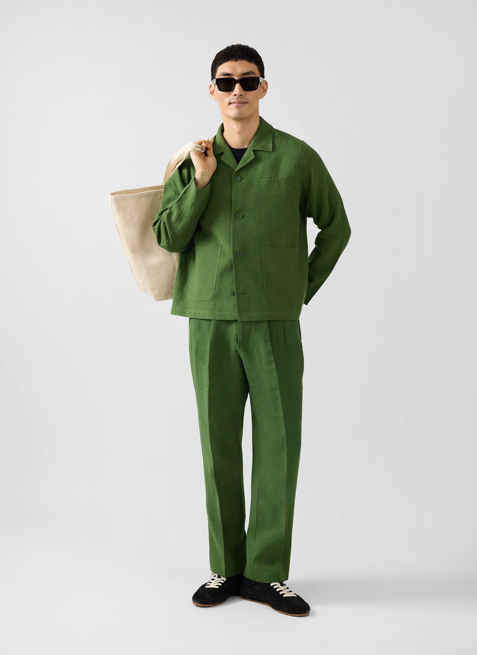 A model wears the Percival Linen Overshirt in Forest green, styled as a suit with matching trousers, sunglasses and a tote.