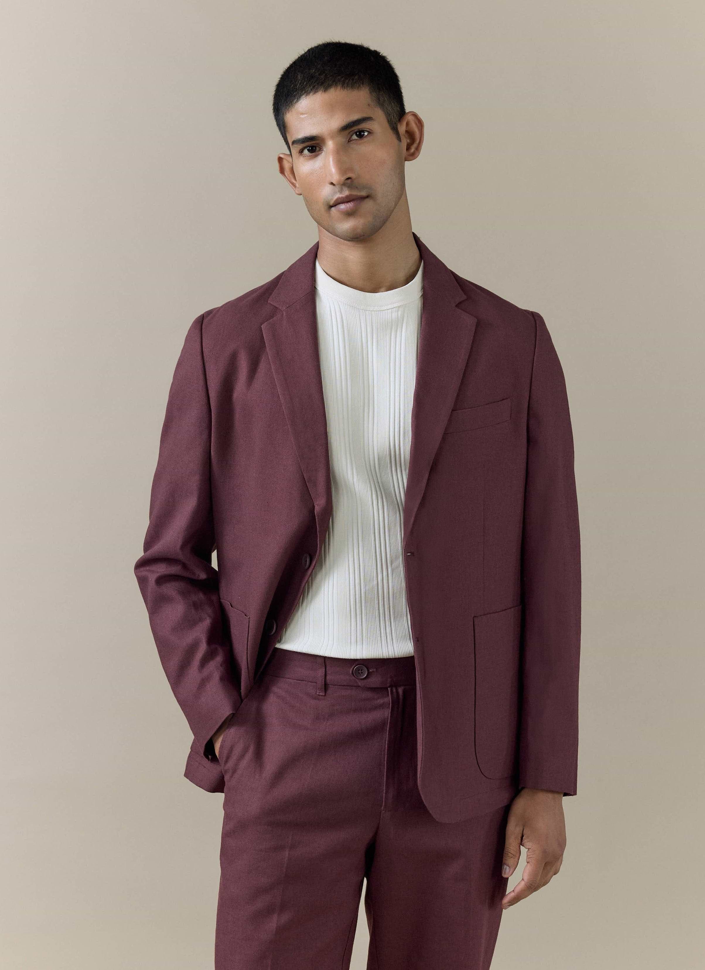 A model wears the Percival Tailored Linen Blazer in Merlot, styled with matching trousers and a white ribbed top.