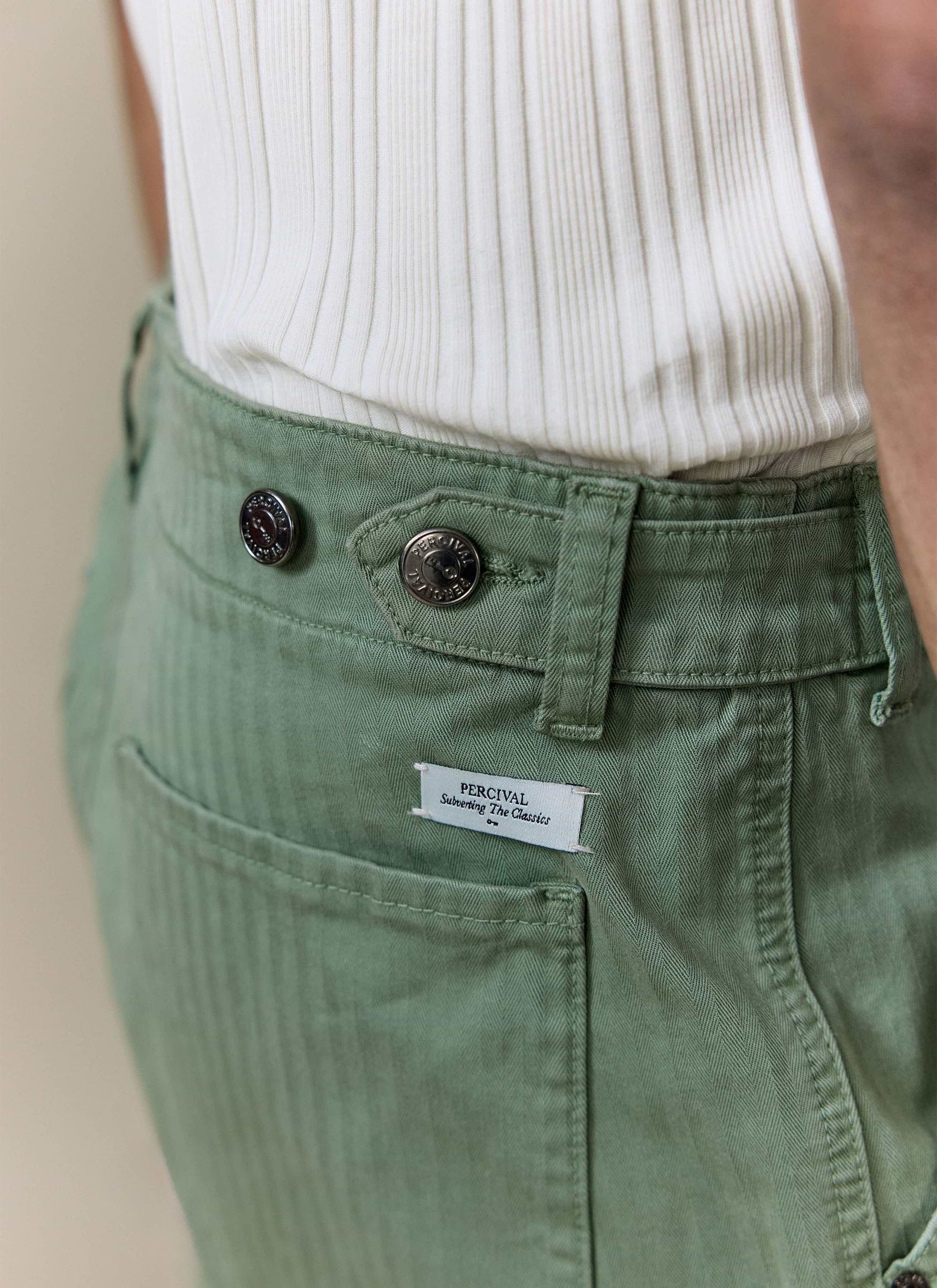 Detailed view of Percival Lungo Herringbone Straight Trousers in sage green cotton, showing the branded buttons and tag.