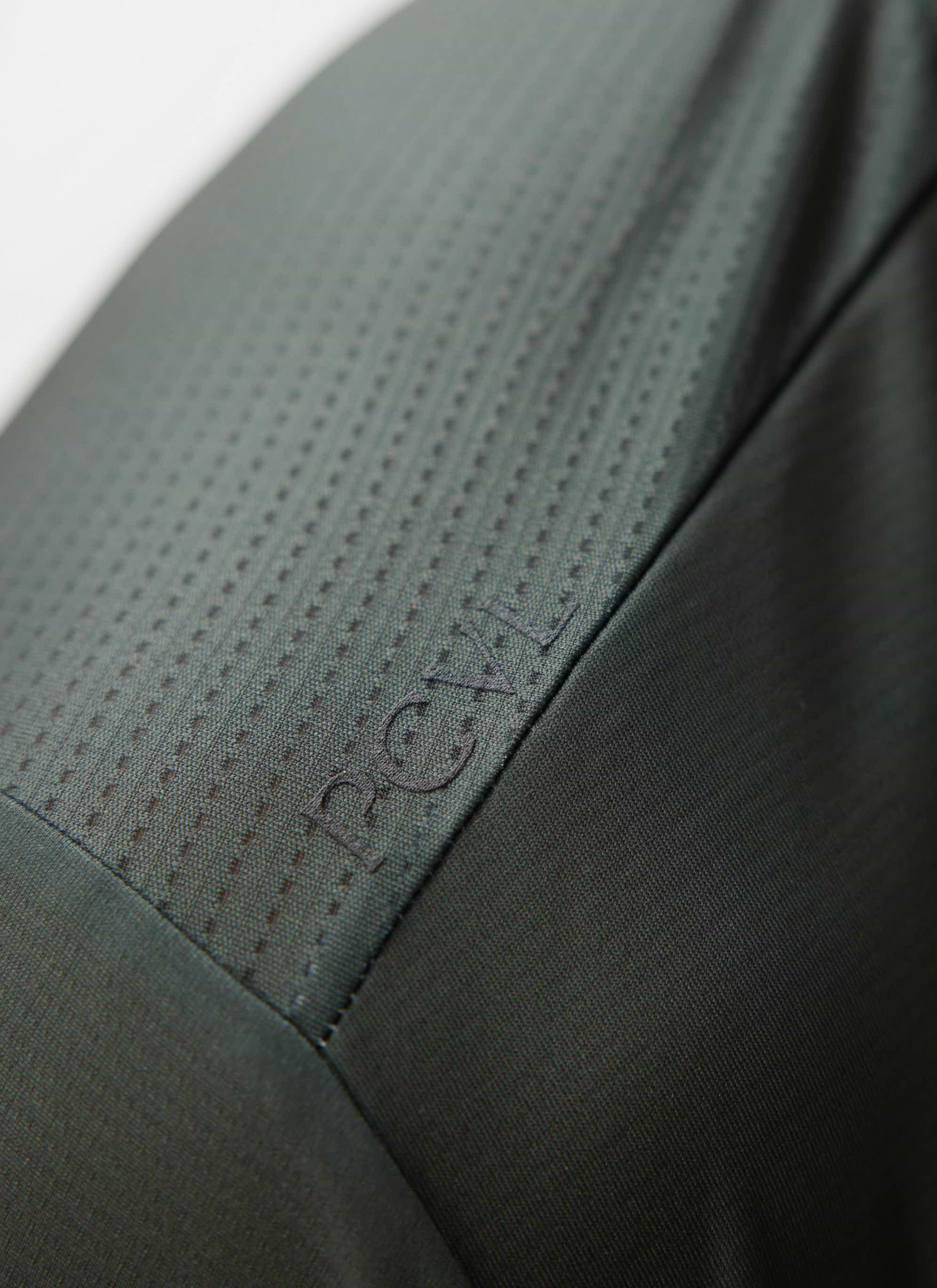 A close-up of the tonal PCVL logo on the ventilated mesh fabric of the Percival Performance Top in forest green.