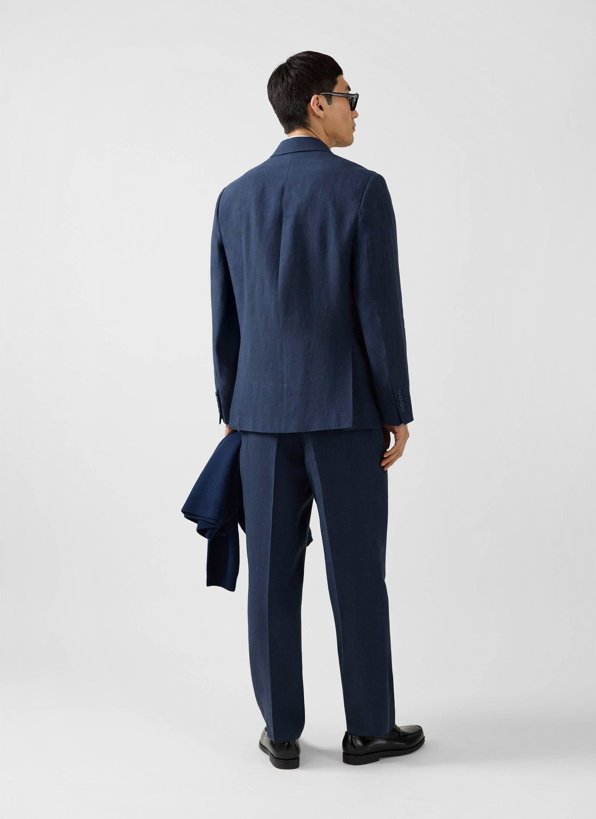 A model viewed from behind wearing the Percival Clifton Double Breasted Blazer and matching trousers in navy linen.