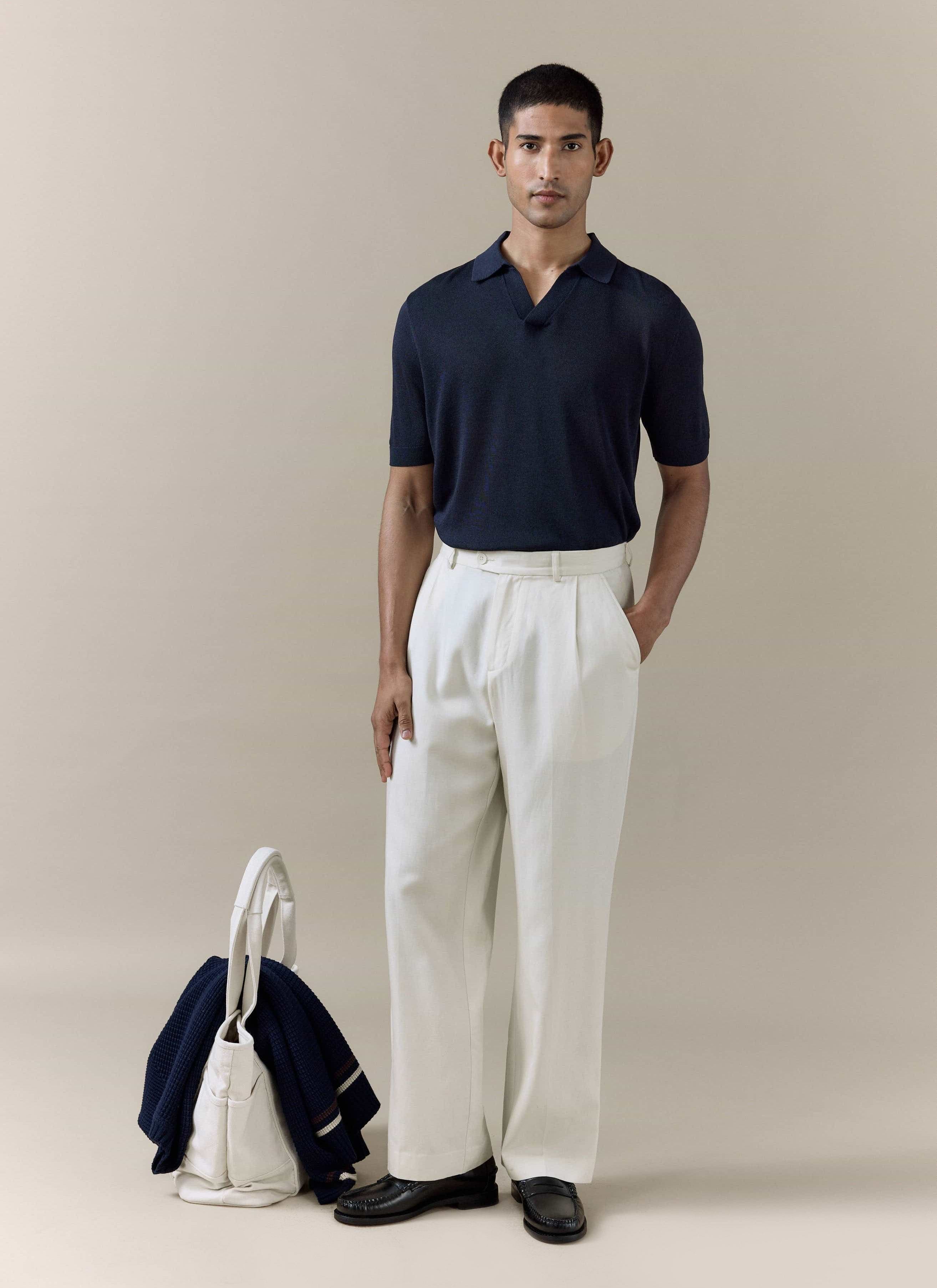 Percival Laurence Knitted Polo in navy linen lyocell blend, paired with off-white pleated trousers and loafers.