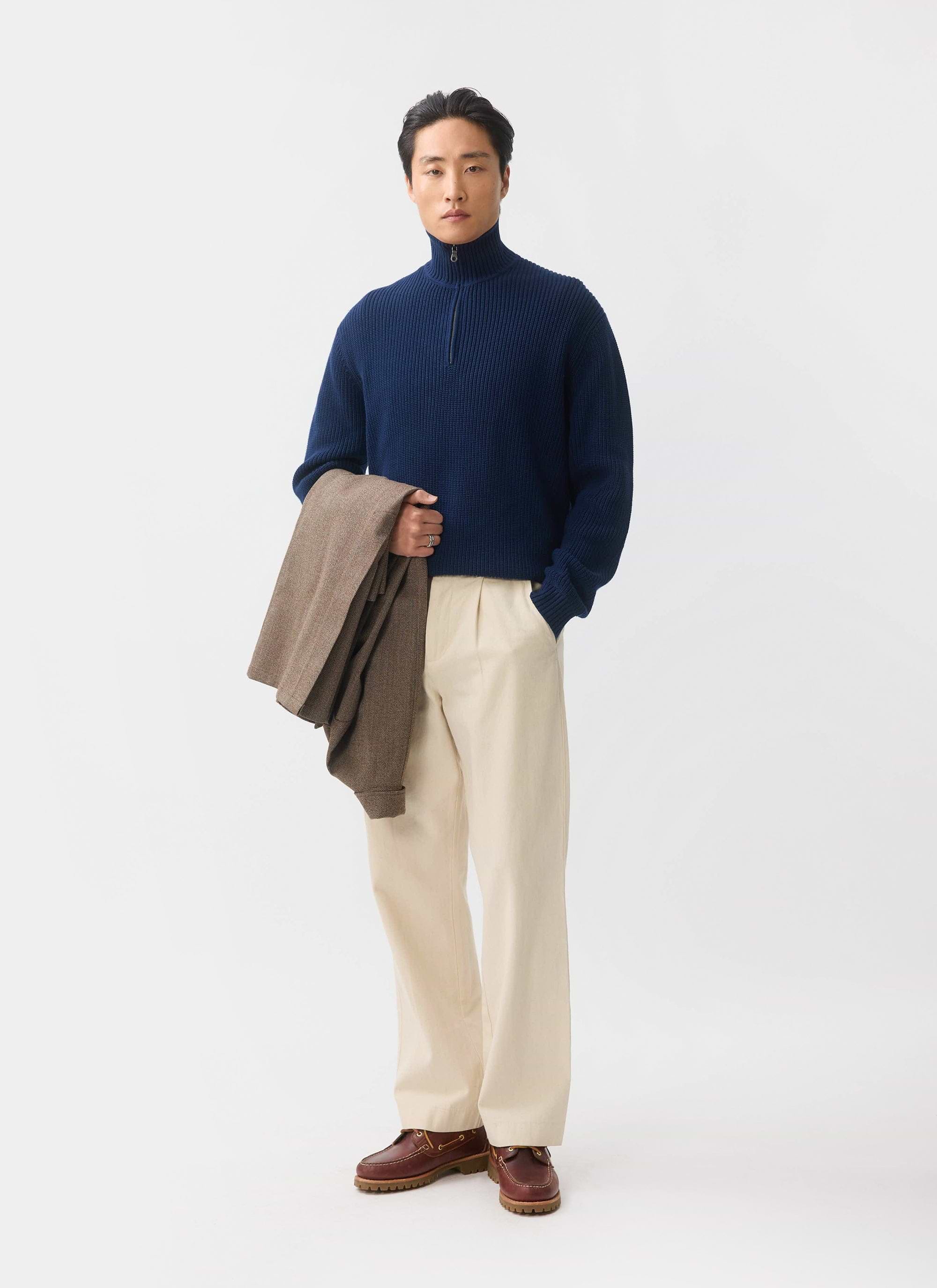 The Percival Meyer Quarter Zip Fisherman in blue, styled on a model with cream trousers and a brown jacket.