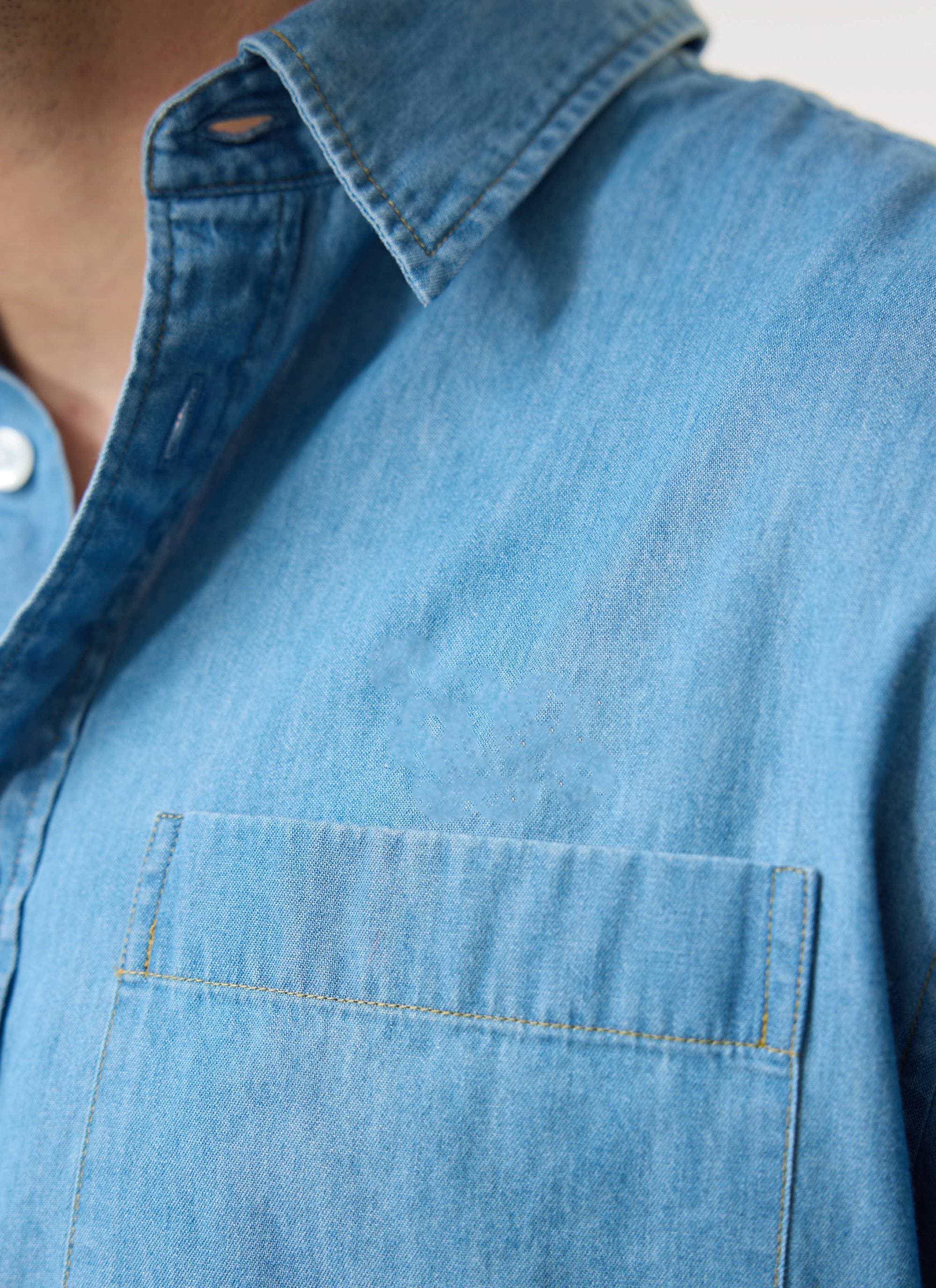 A close-up of the Percival Marco Pearce denim shirt in light wash blue, showing the texture, collar and chest pocket.