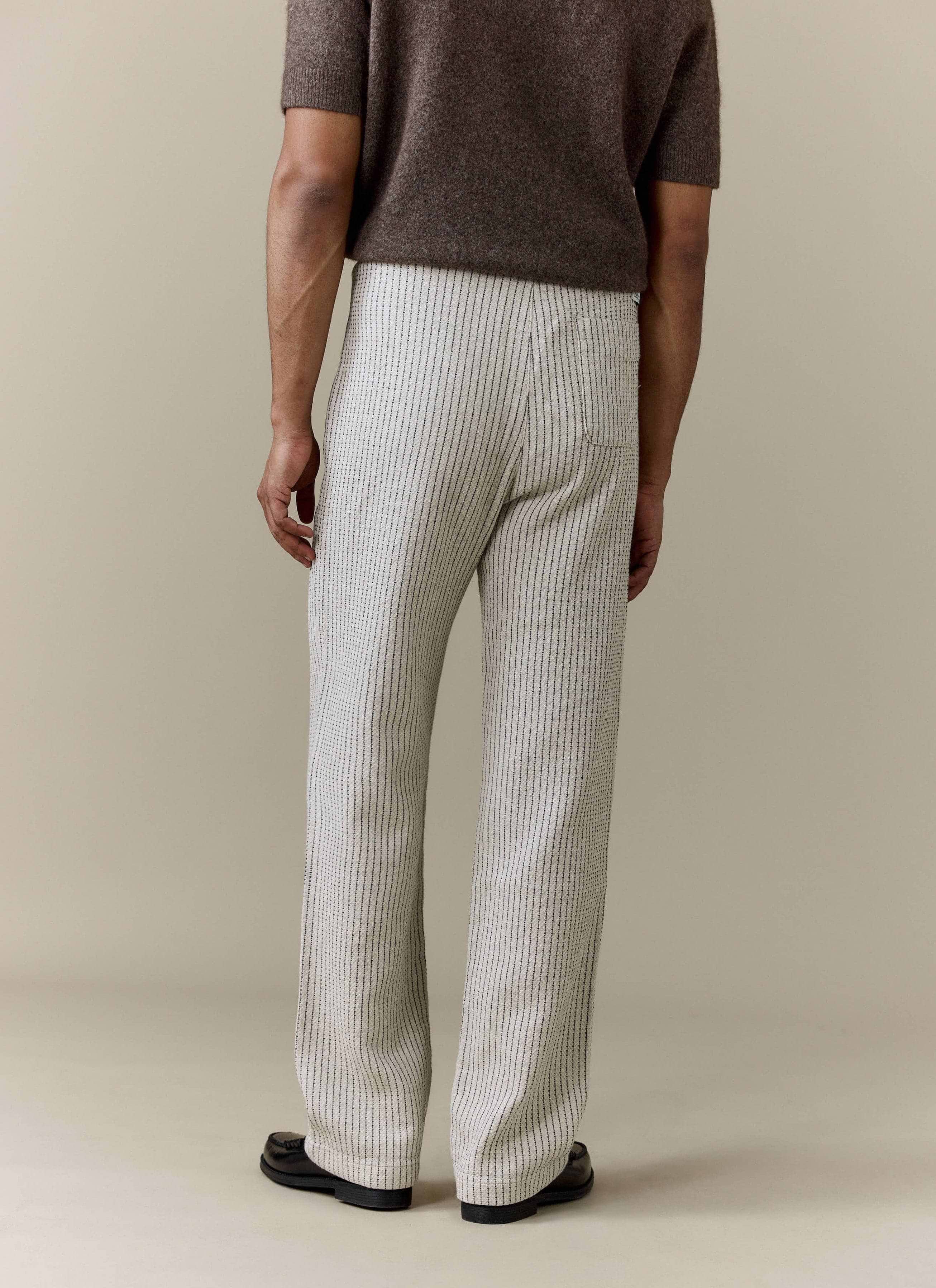 A rear view of a model wearing the ecru linen Sorrento Wide Leg Trousers from Percival, showing off the relaxed fit.