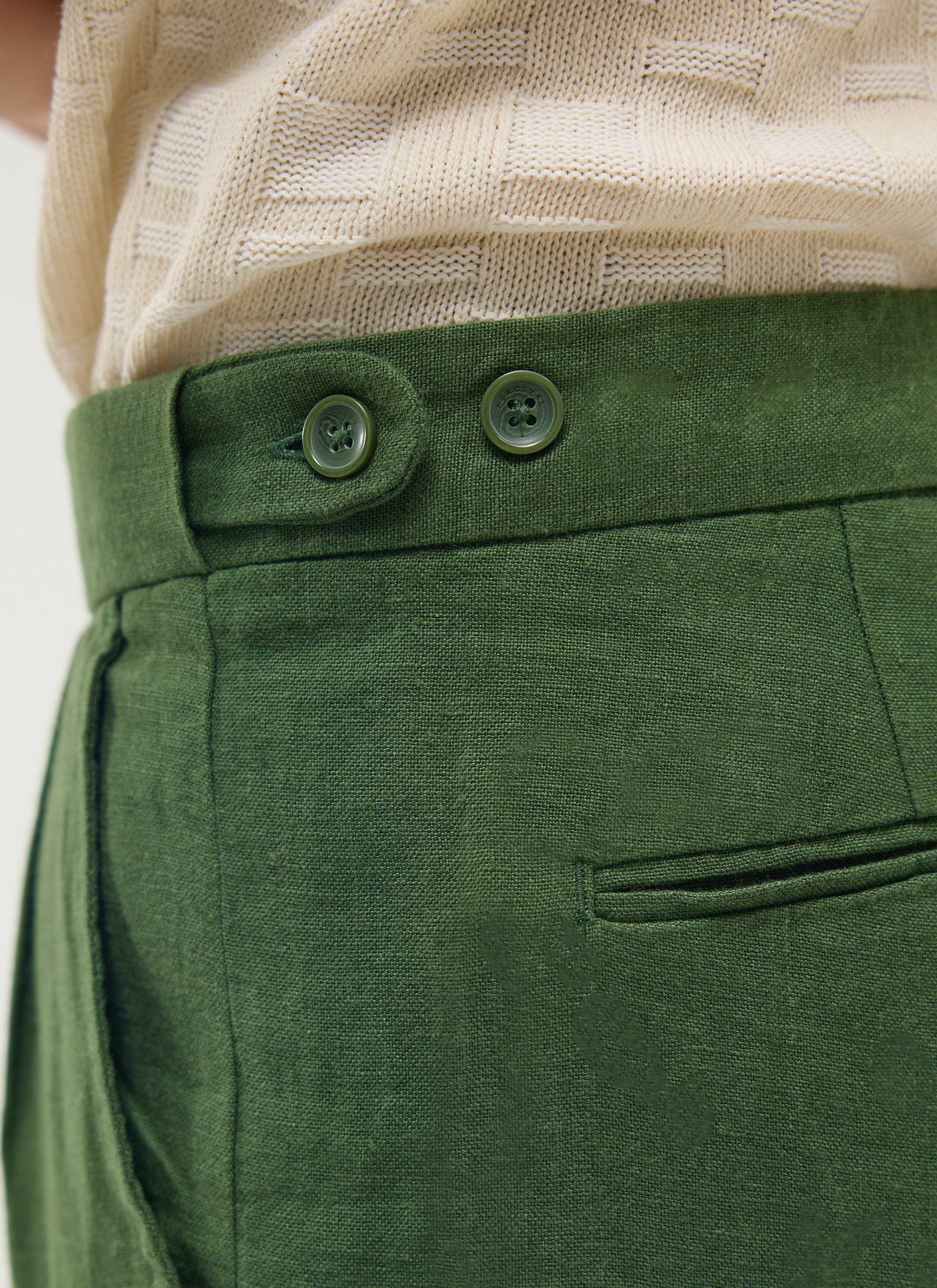 Close-up of the waistband on the Percival Pleated Tailored Trousers in forest green linen, showing the button detail.