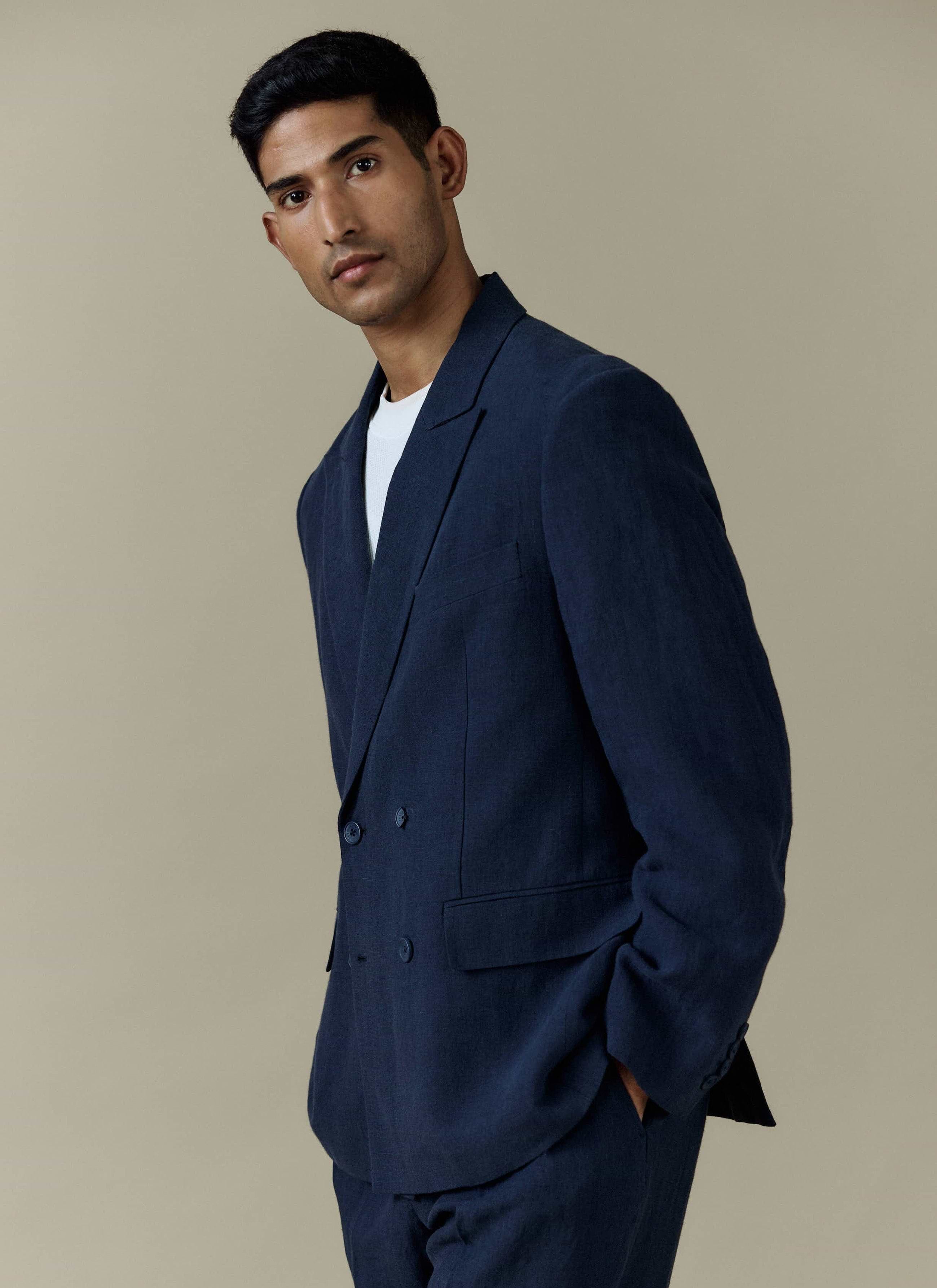 A model wears the navy linen Clifton Double Breasted Blazer from Percival over a white t-shirt.
