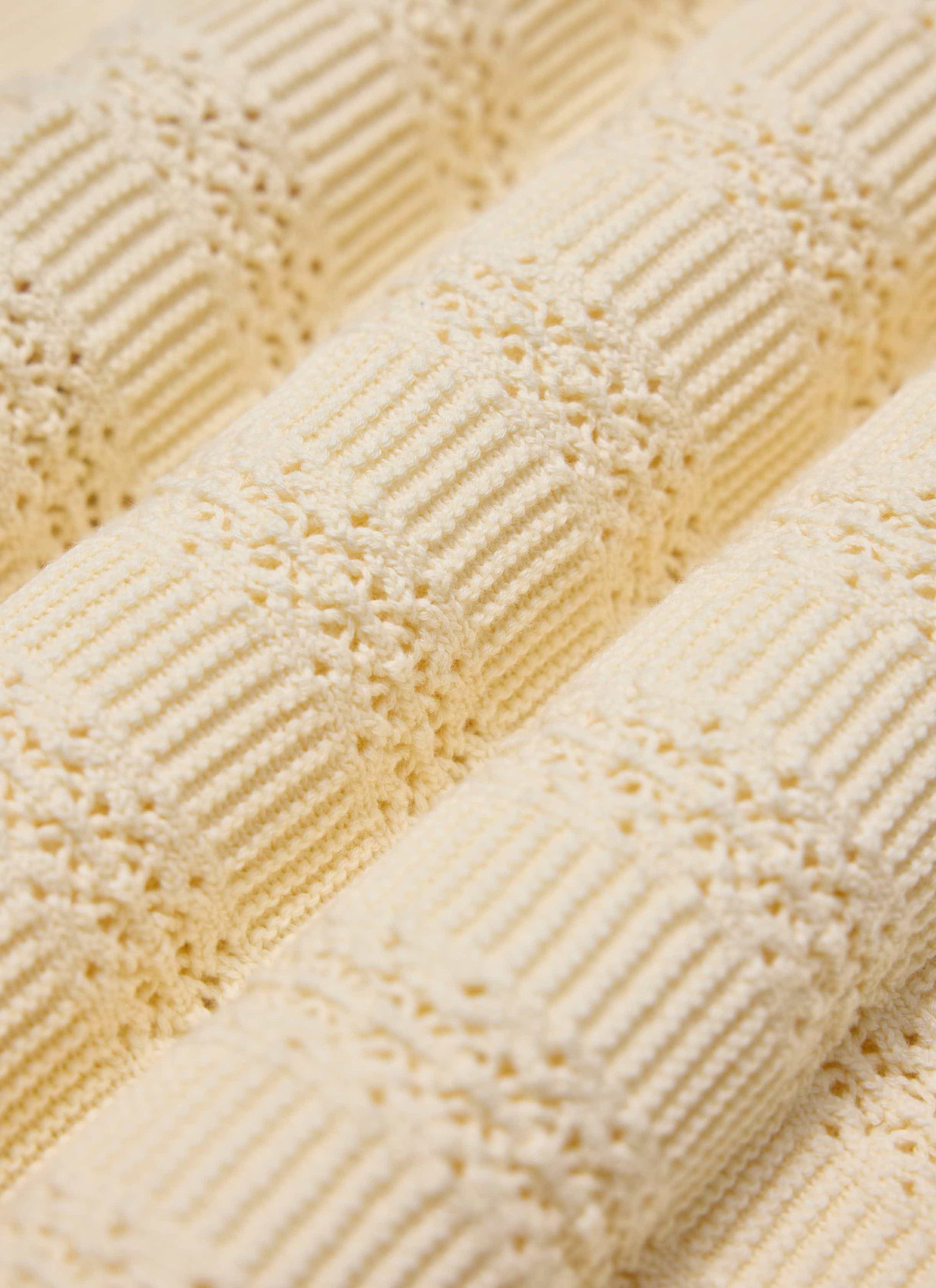 A close-up of the tonal book spine jacquard texture on the ecru Addendum Knitted Polo Shirt from Percival.